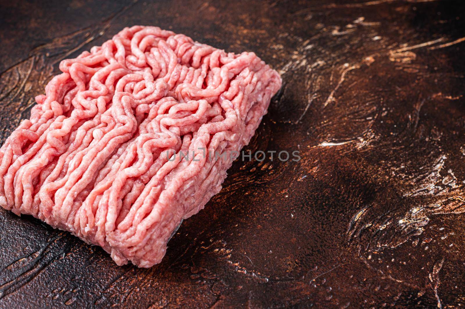 Raw ground chicken or turkey meat on brown table. Dark background. Top View. Copy space by Composter