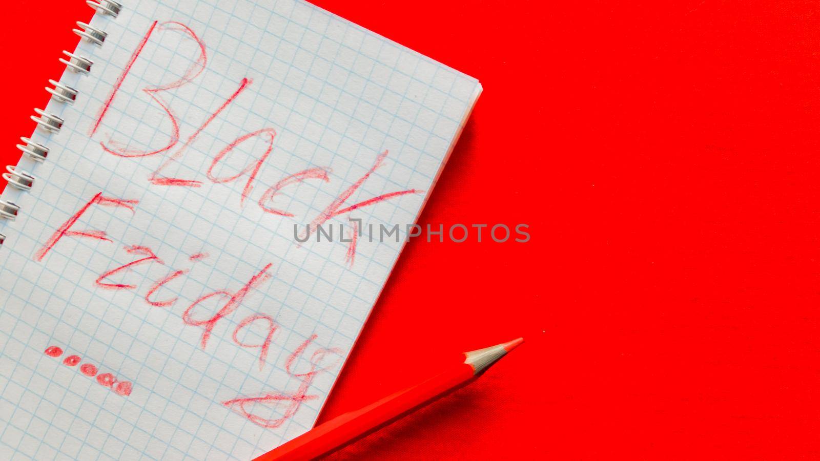 Black friday sale text written on a notepad with a red pencil on a red background. Background, holiday concept. Black Friday - International Day of Shopping, Promotions, Discounts, Sales. Sales season is the fourth Thursday of November. Copy space, place for text, flat lay.