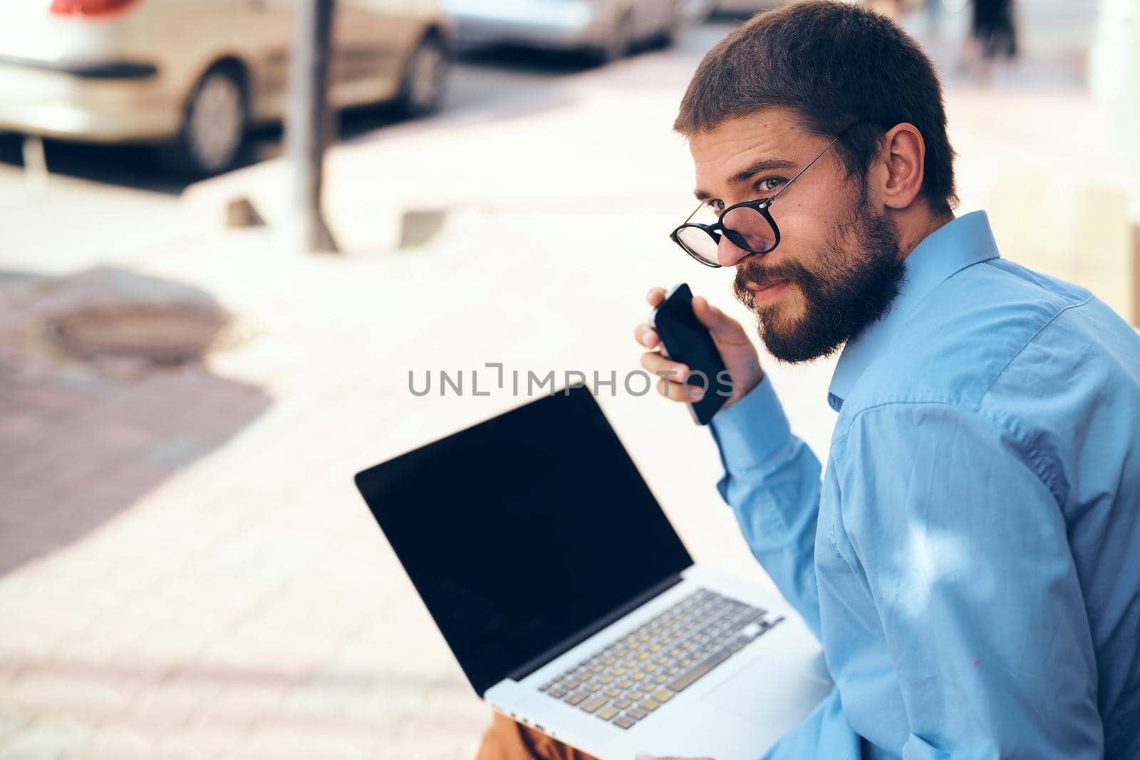 a man in a blue shirt on the street with a laptop manager. High quality photo