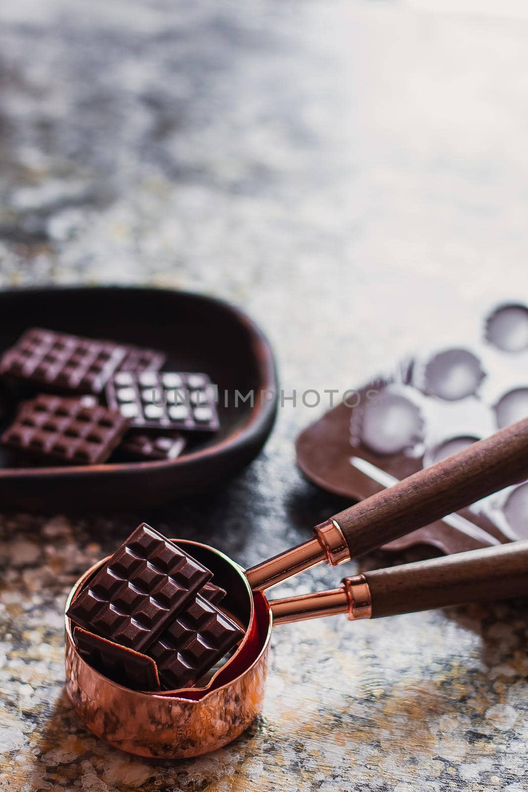 Assortment of different chocolate types in wooden carved plate, with vintage props on the background