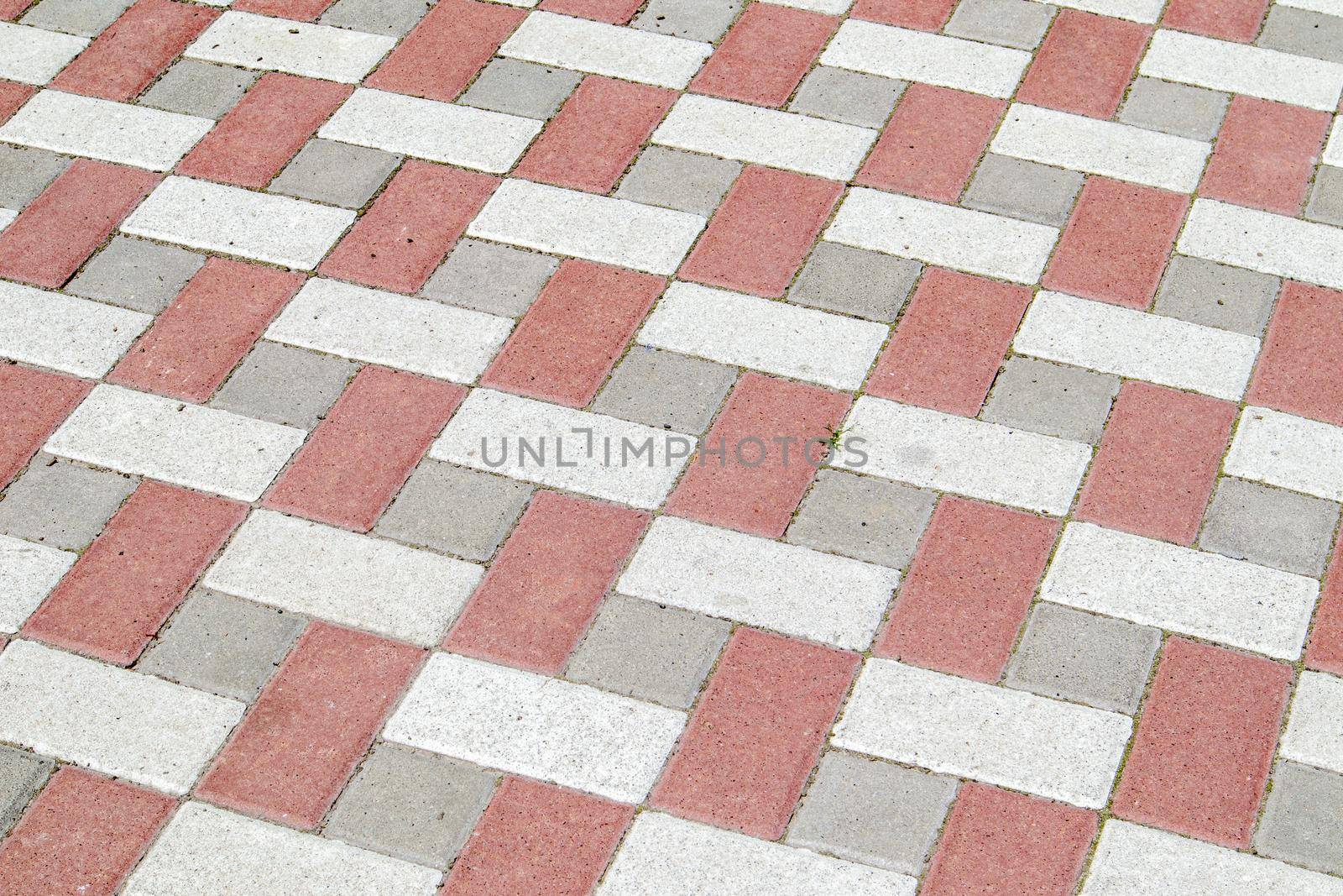 Concrete or paved newly laid gray and red paving slabs or stones for floors or walkways. Concrete paving slabs in the backyard or road paving. Garden brick path in the courtyard on a sandy foundation
