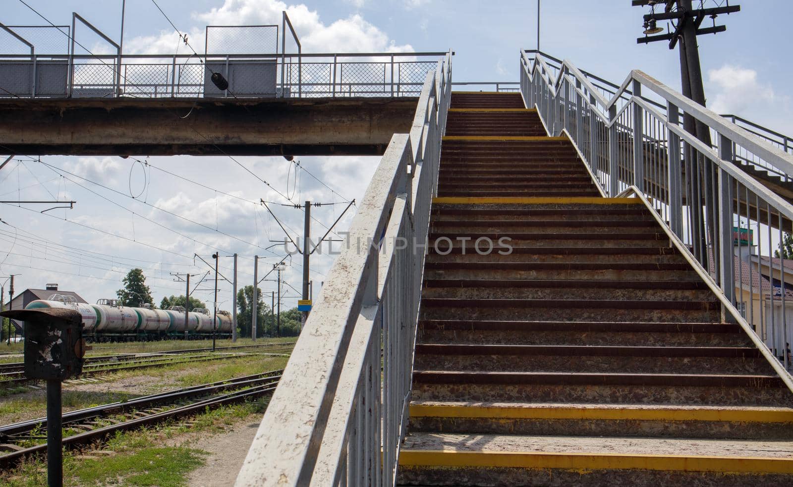 Railway bridge with steps, with impressive steps in perspective. Overhead pedestrian crossing. Bridge stairs connecting one platform to another at the train station. Ukraine, Kiev - August 19, 2021