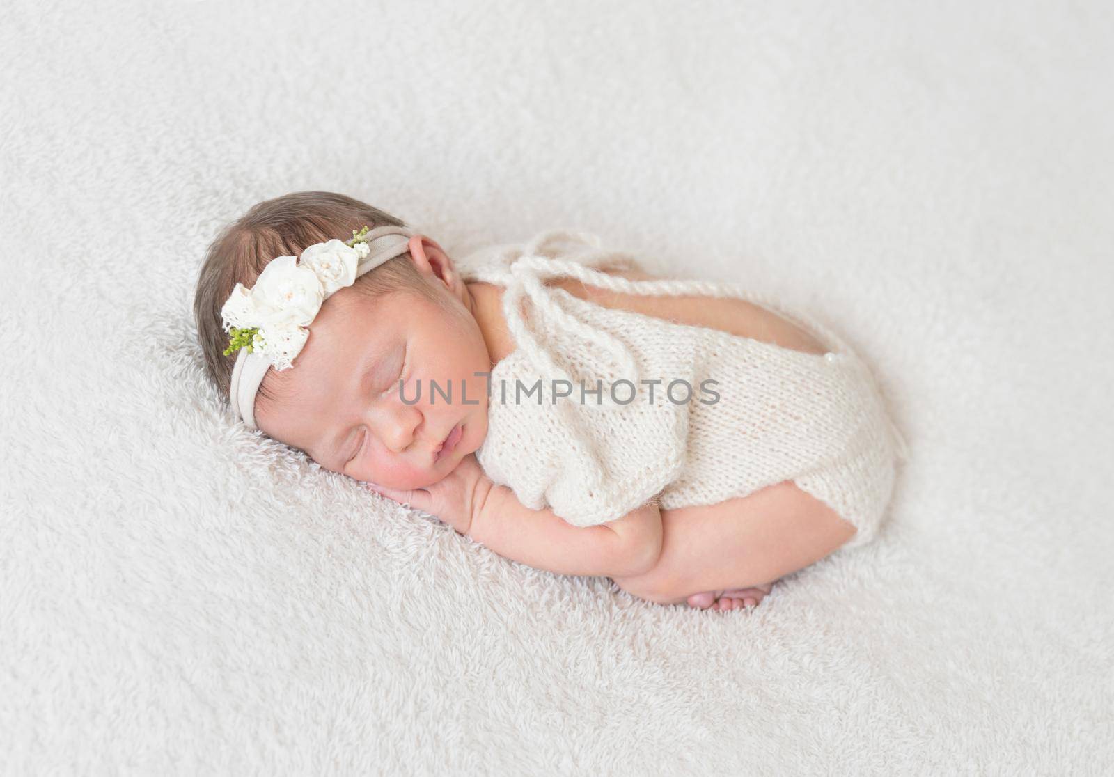 Cute infant sleeping wearing wonderful white warm suit with a cut on the back