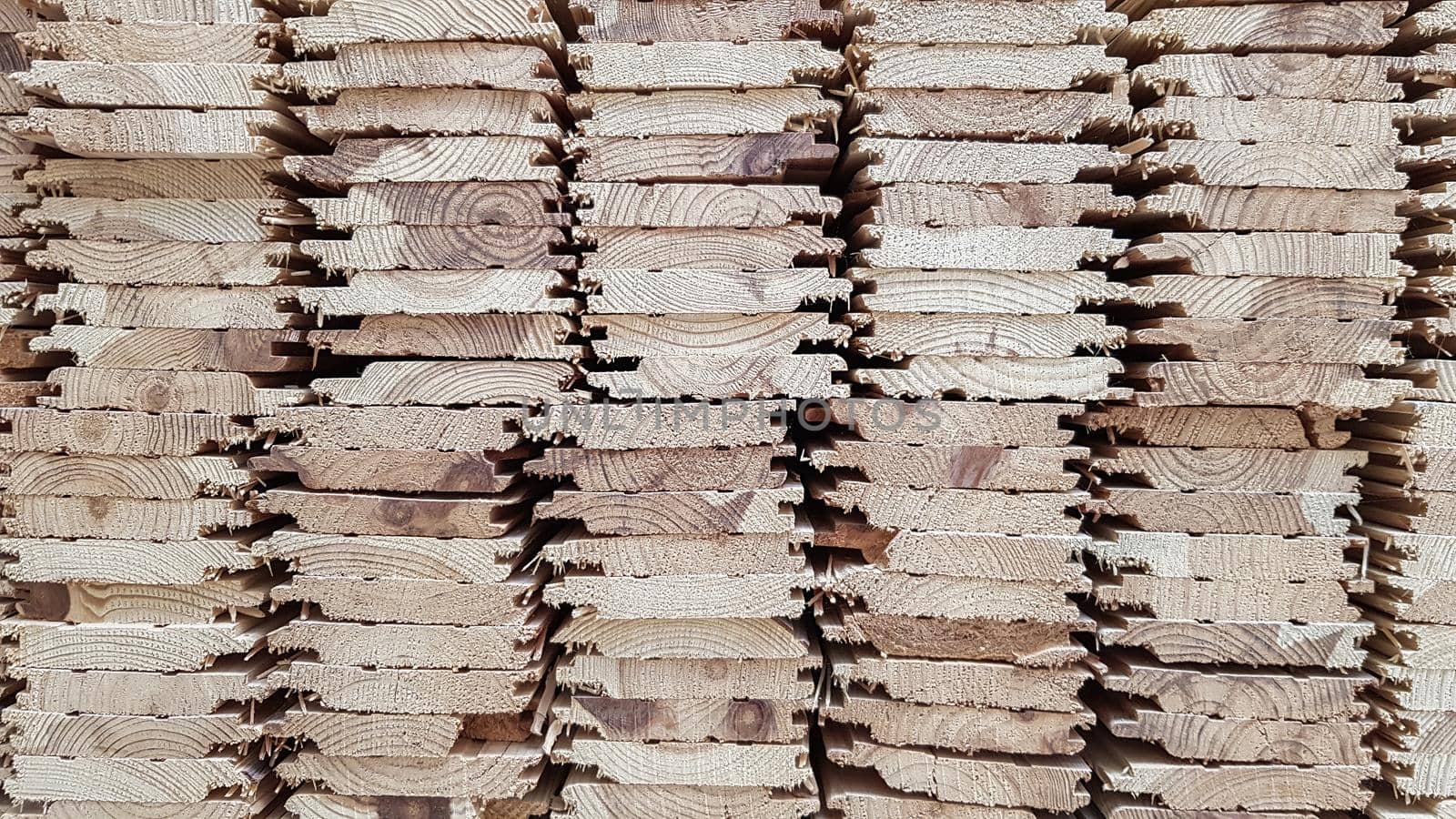 A pile of new wooden boards in stock. Production line of a factory of wooden floors. Industrial background.