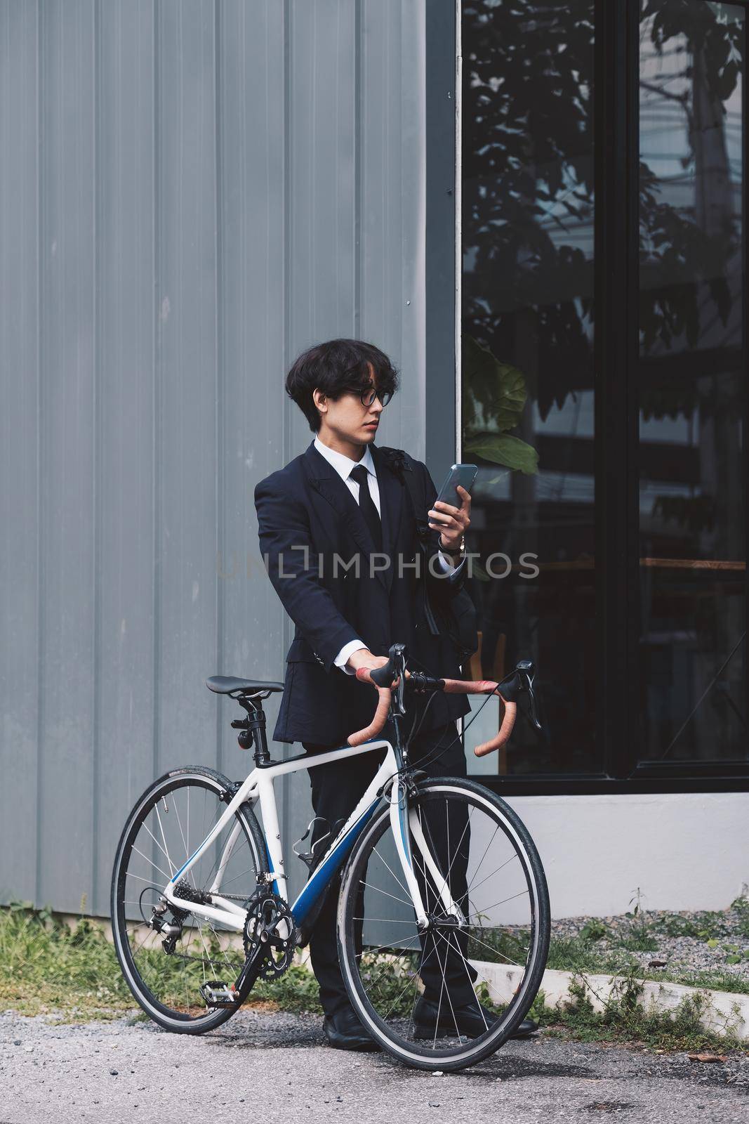 Portrait asian businessman pushing his bicycle in the morning with mobile phone by nateemee