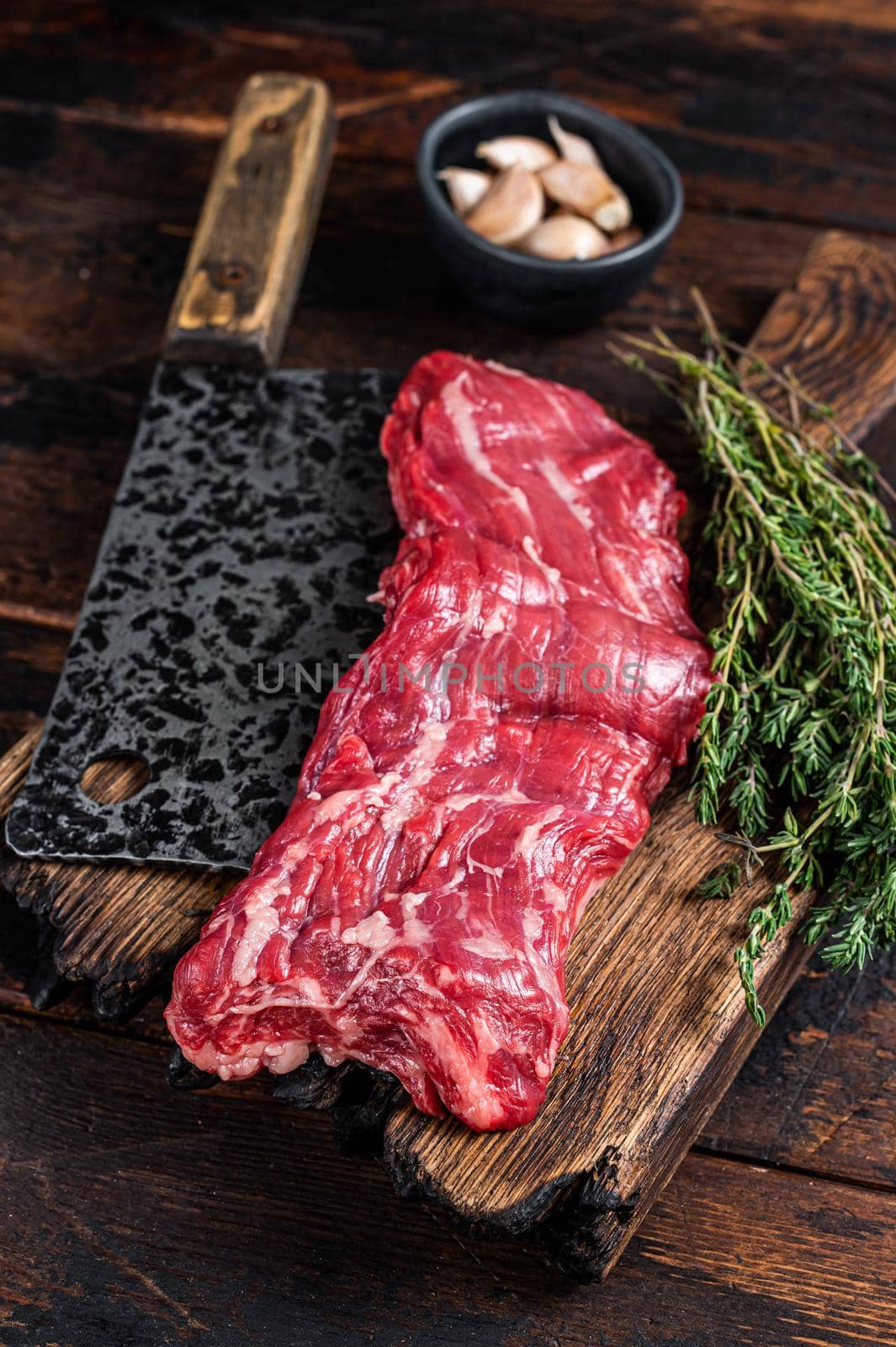 Raw machete skirt beef steak on butcher board with cleaver. Dark wooden background. Top view by Composter