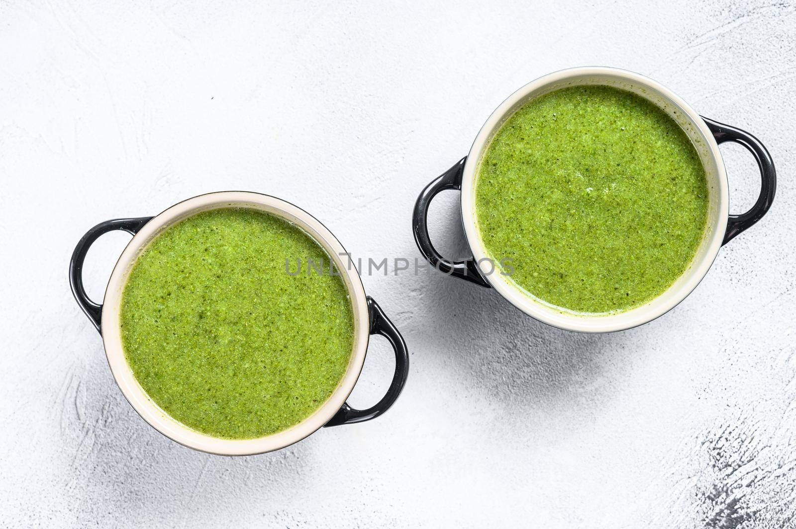 Homemade broccoli and spinach cream soup in bowl. White background. Top view.