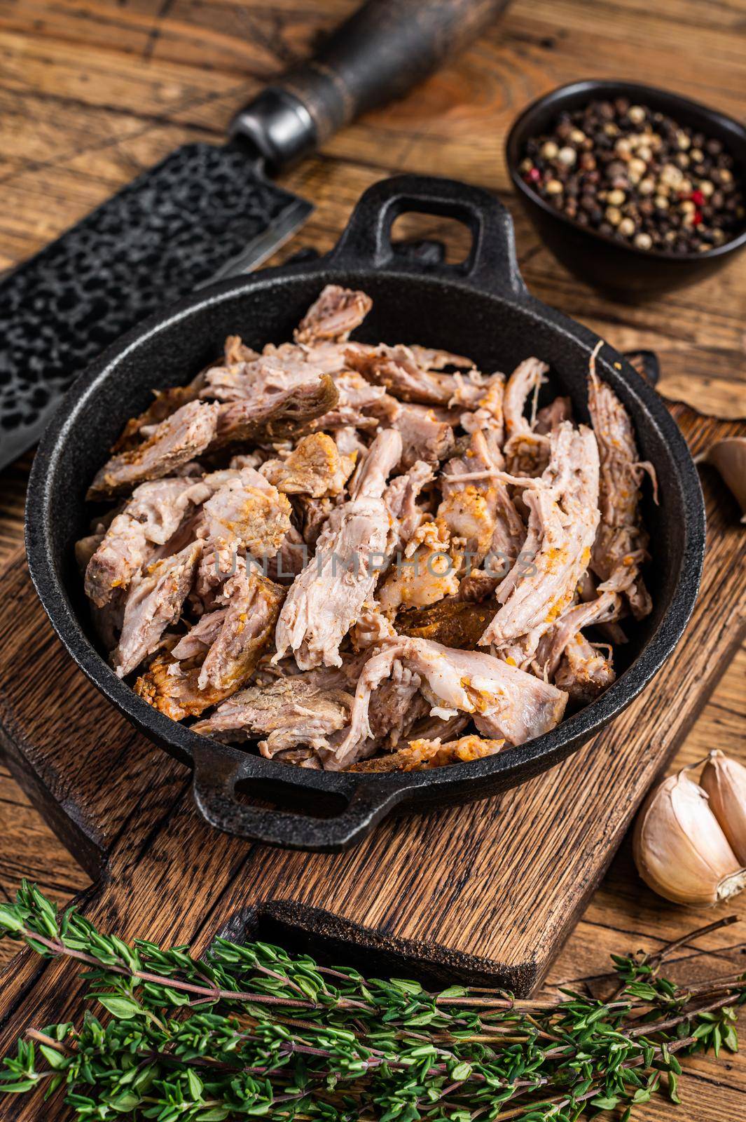 Slow shredded puilled pork meat in a pan with butcher knife. wooden background. Top view by Composter