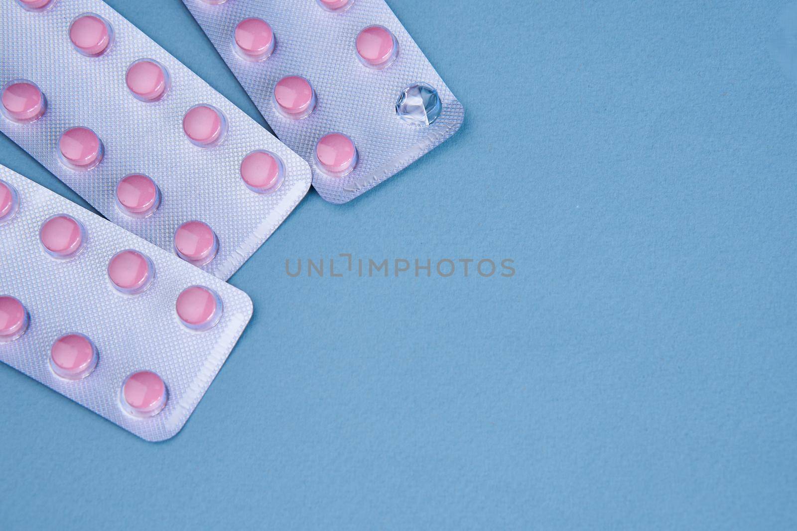 pink pills in packs vitamins pain reliever blue background. High quality photo