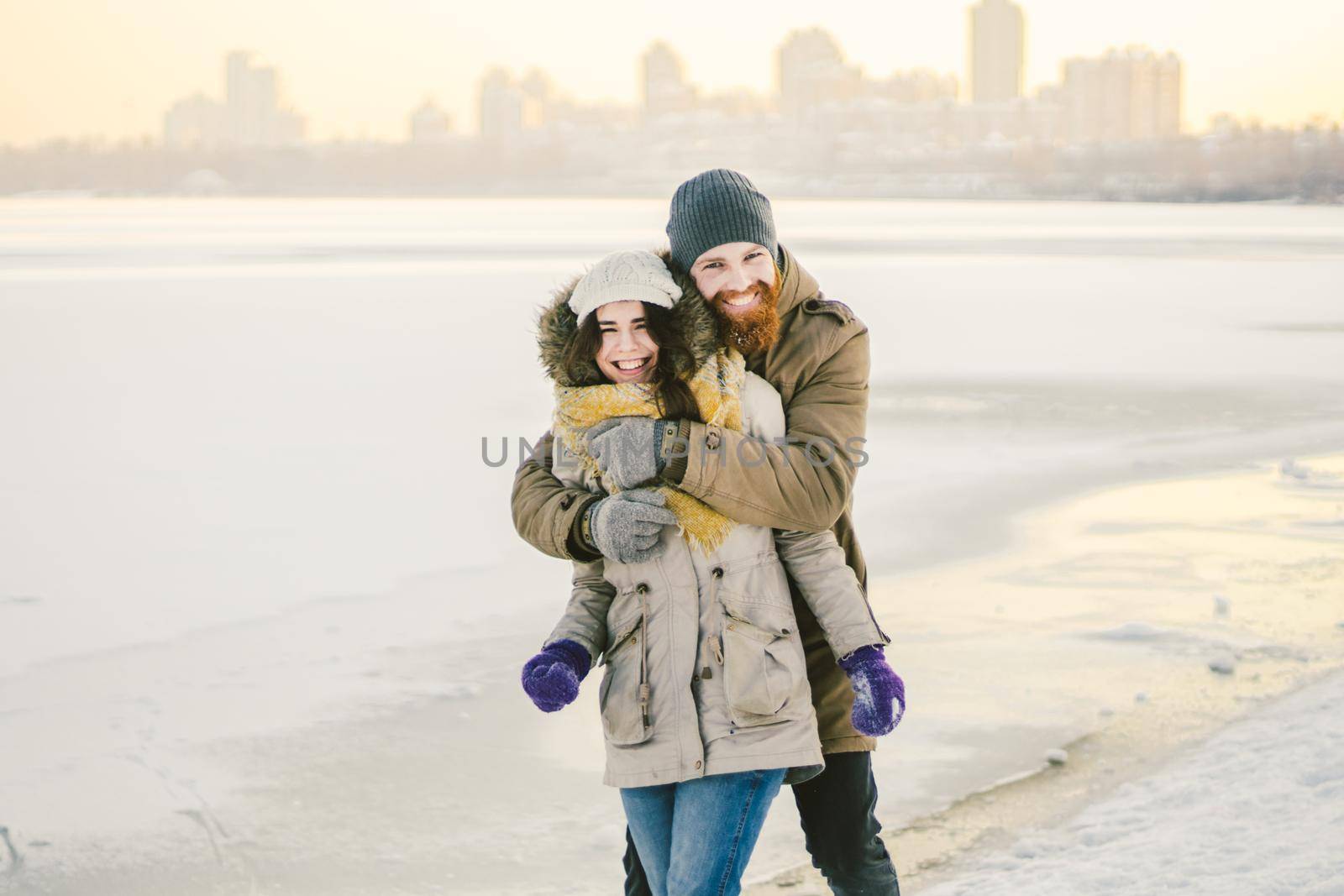 Young couple cheerfully flounders in snow. Between comic fight. Happy young couple hugs in winter snowy woods. Romantic lifestyle men and women in love. St. Valentine Day date Christmas hugging happy by Tomashevska