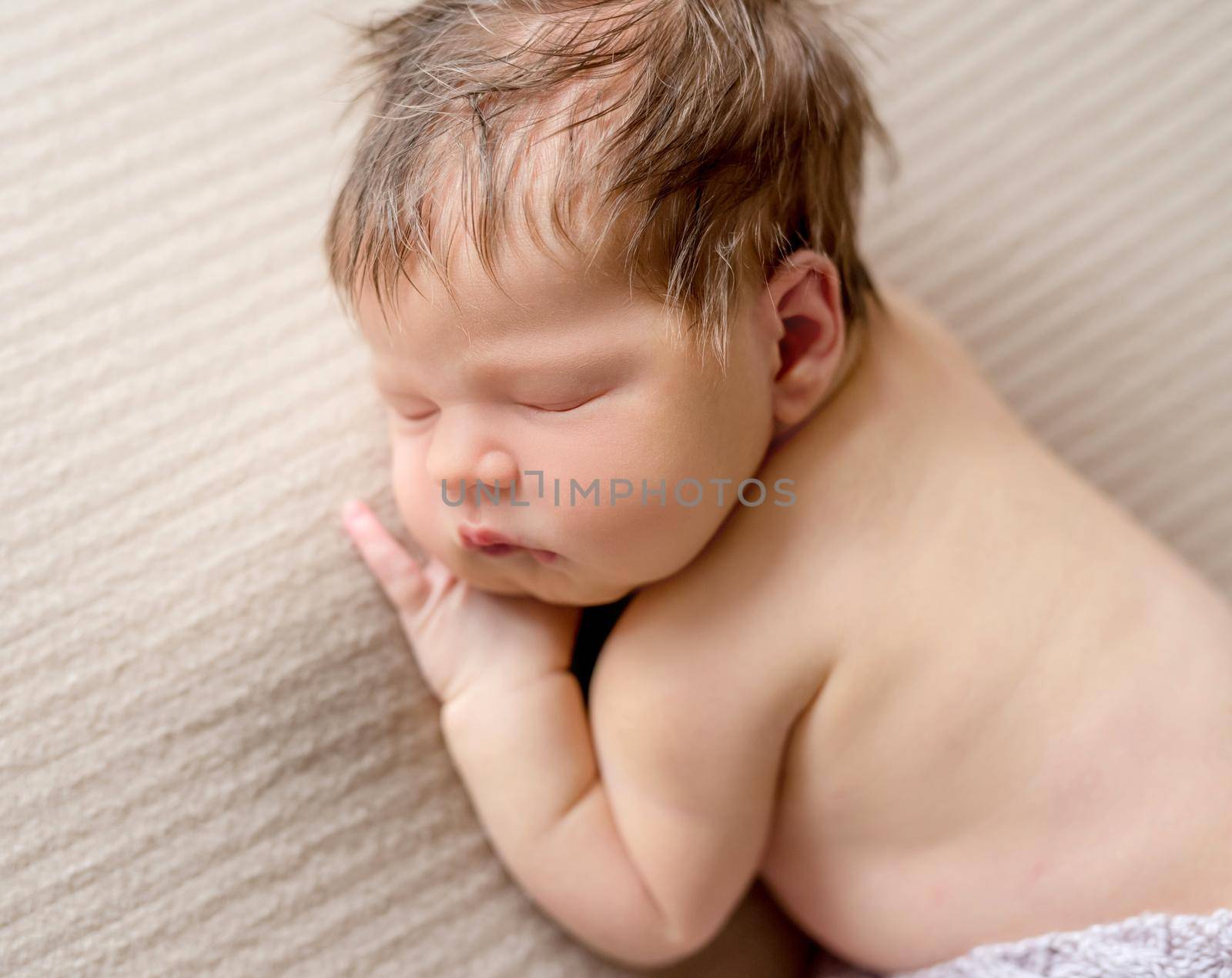 Cute little baby sweetly sleeping on the striped blanket