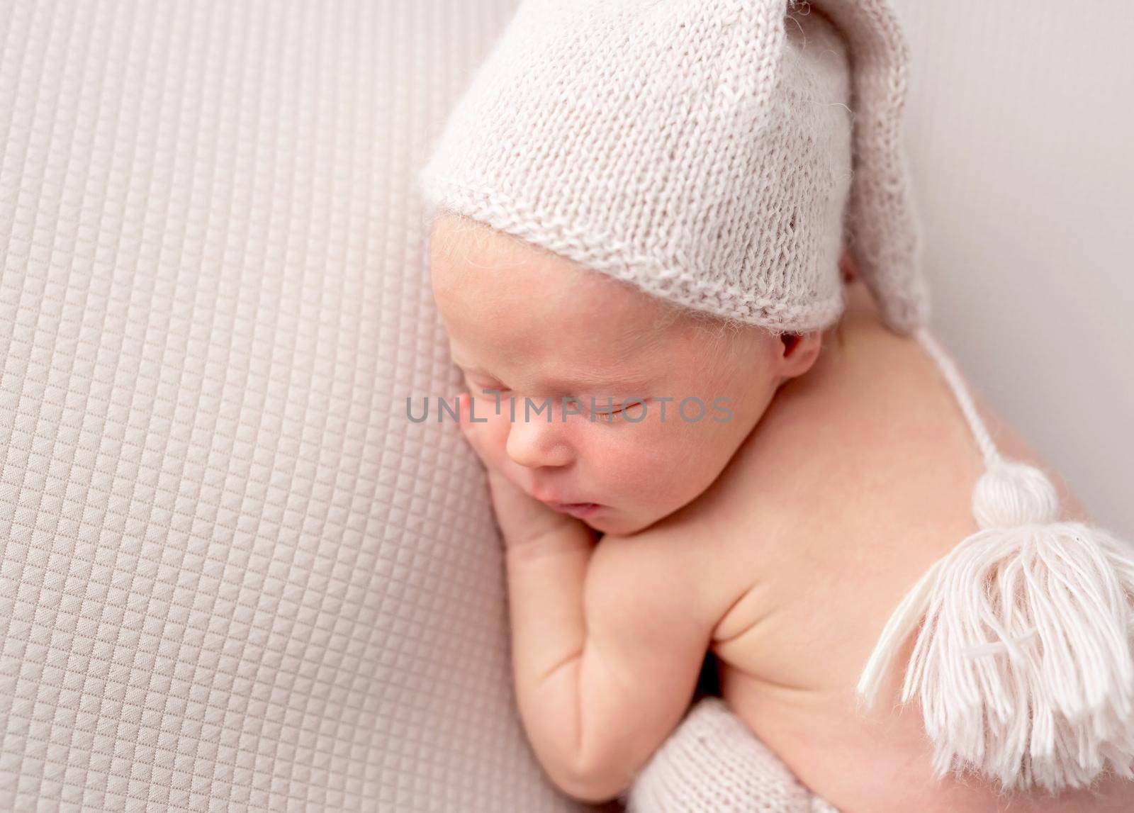 Cute baby in white knitted hat and pants sweetly sleeping