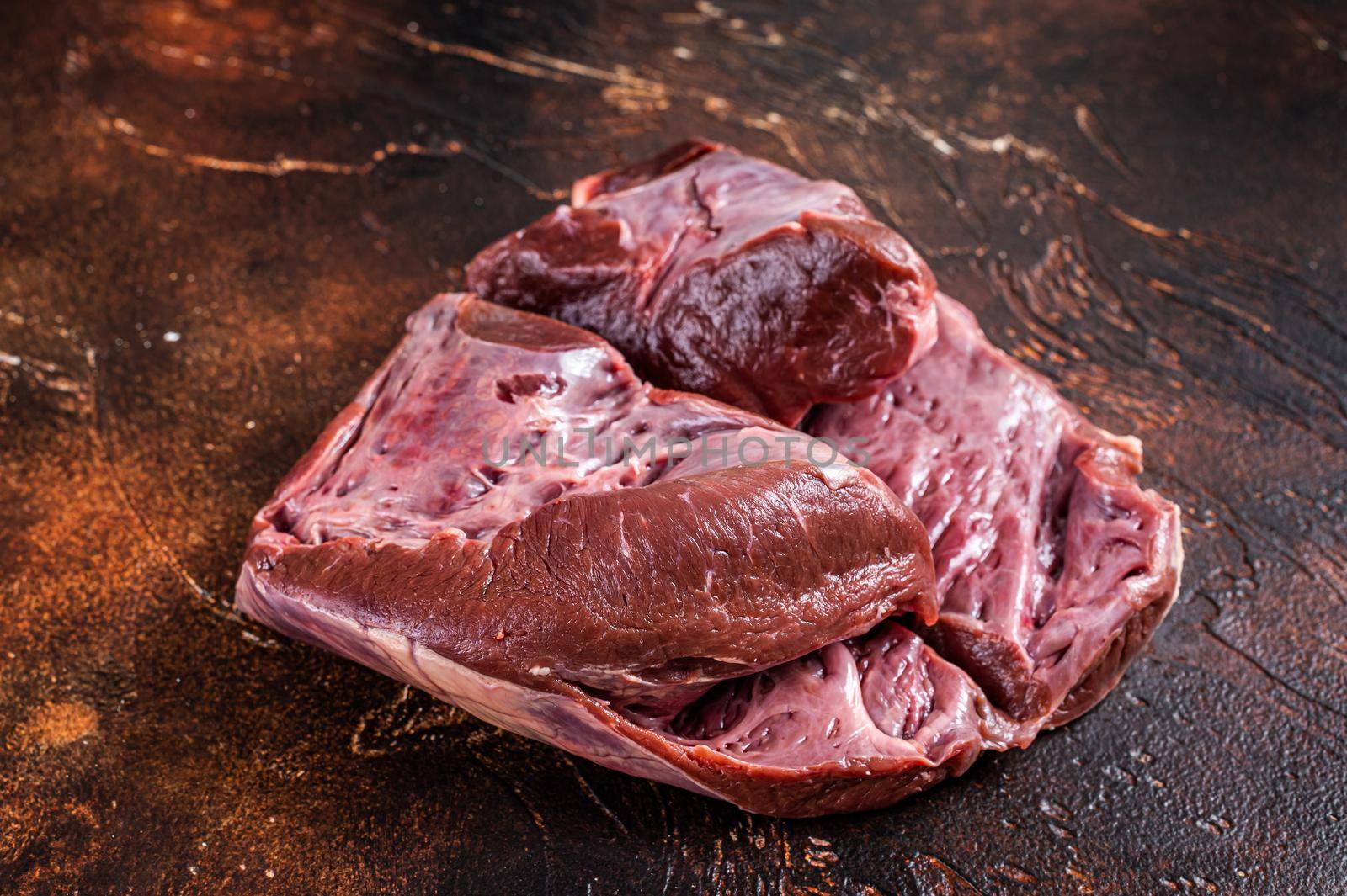 Cut Beef or veal raw heart on a butcher table. Dark background. Top View by Composter