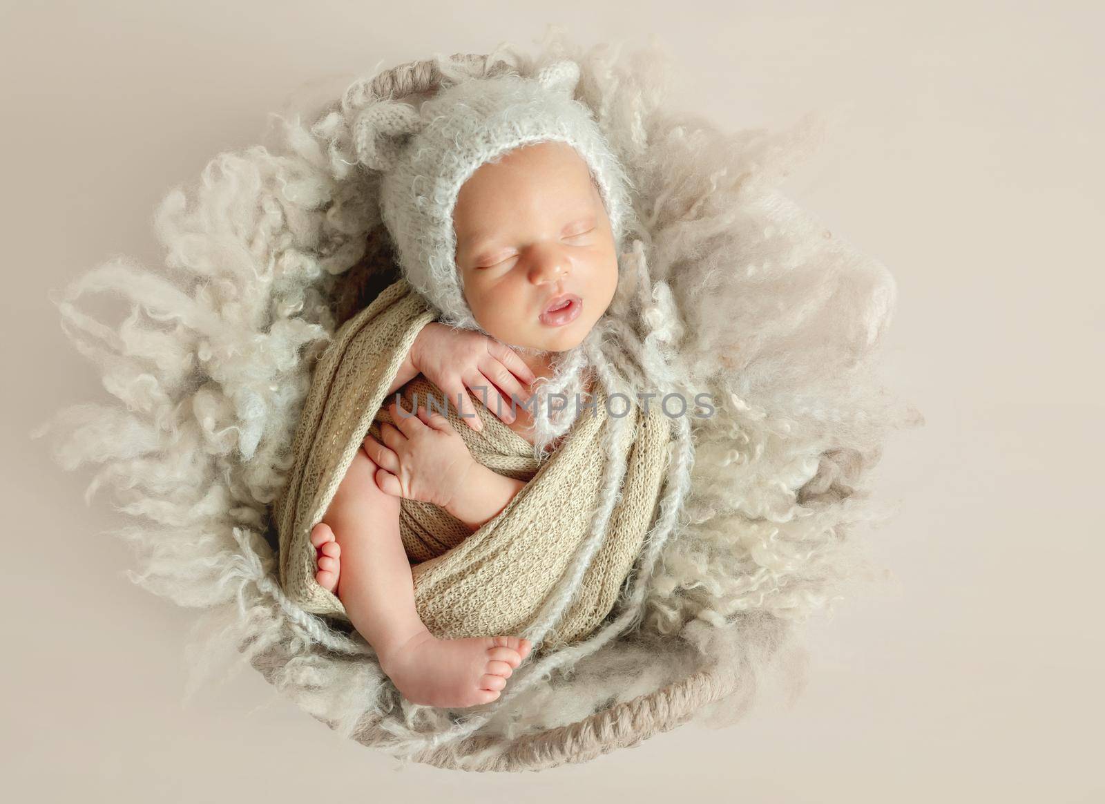 Adorable newborn child sleeping on fluffy wool blanket in little knitted hat