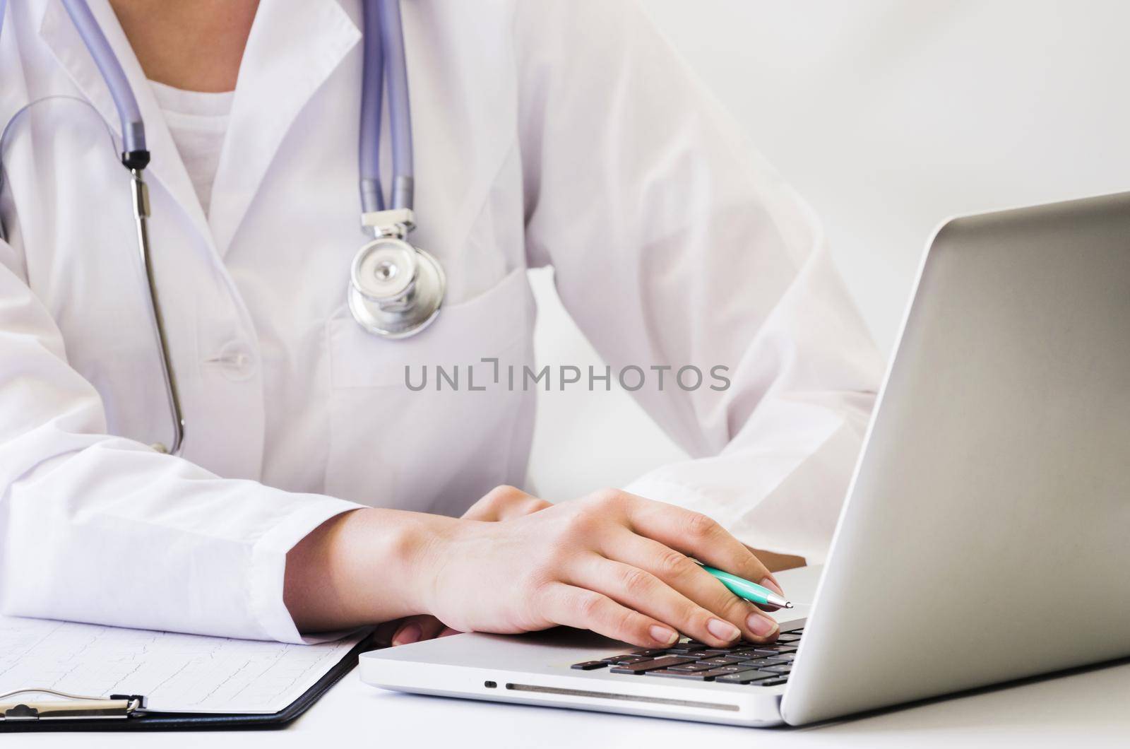 female doctor with stethoscope around her neck using laptop desk