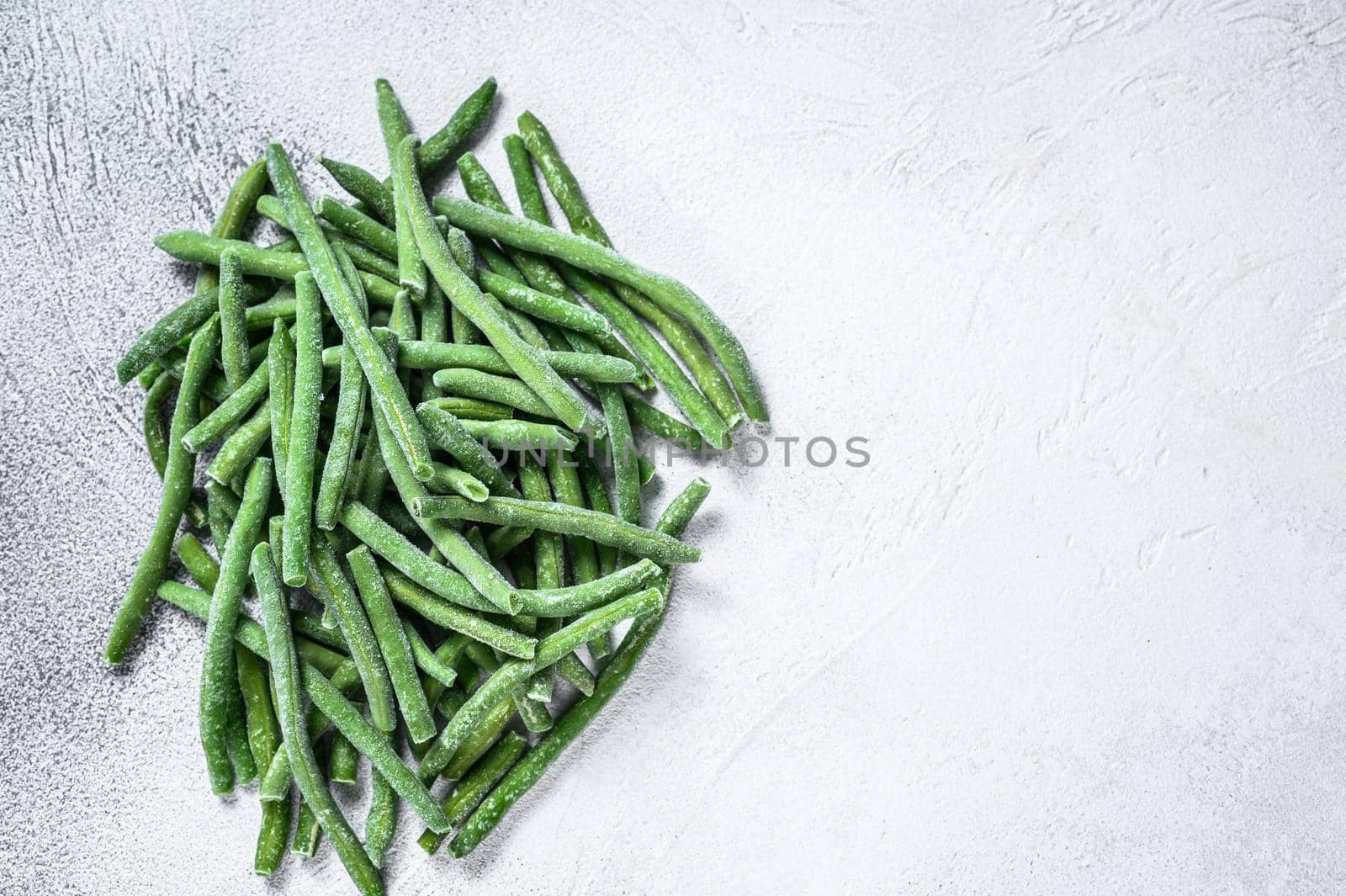 Frozen green beans on the white kitchen table. White background. top view. Copy space.