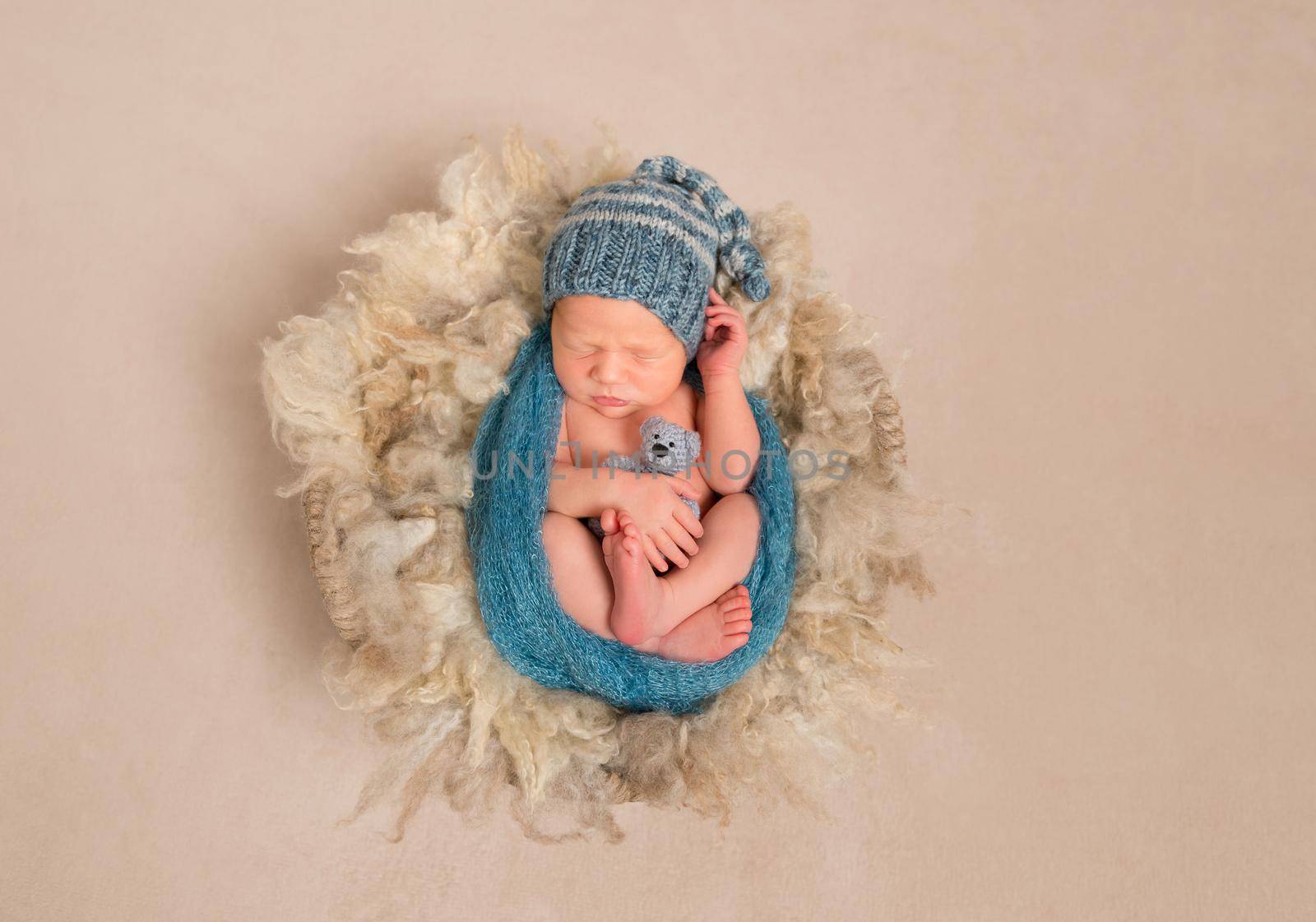 Little kid wrapped in a blue scarf in a hat resting, topview