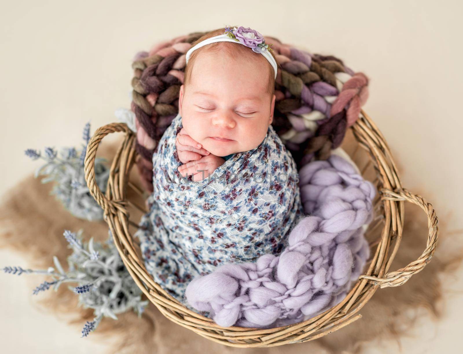 Beautiful newborn wearing diadem in wooden basket