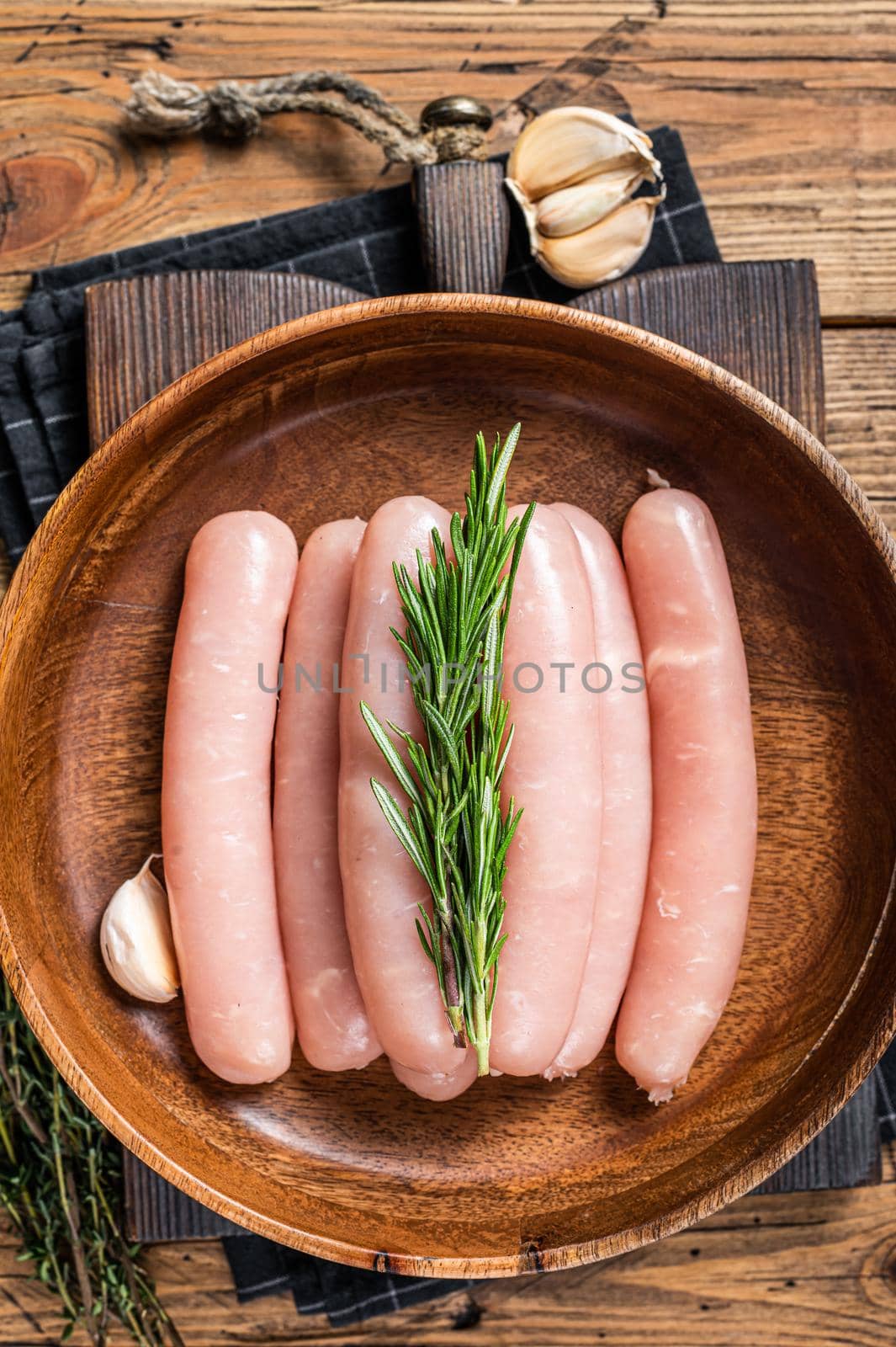 Poultry raw sausages in a wooden palte with herbs. wooden background. Top view by Composter