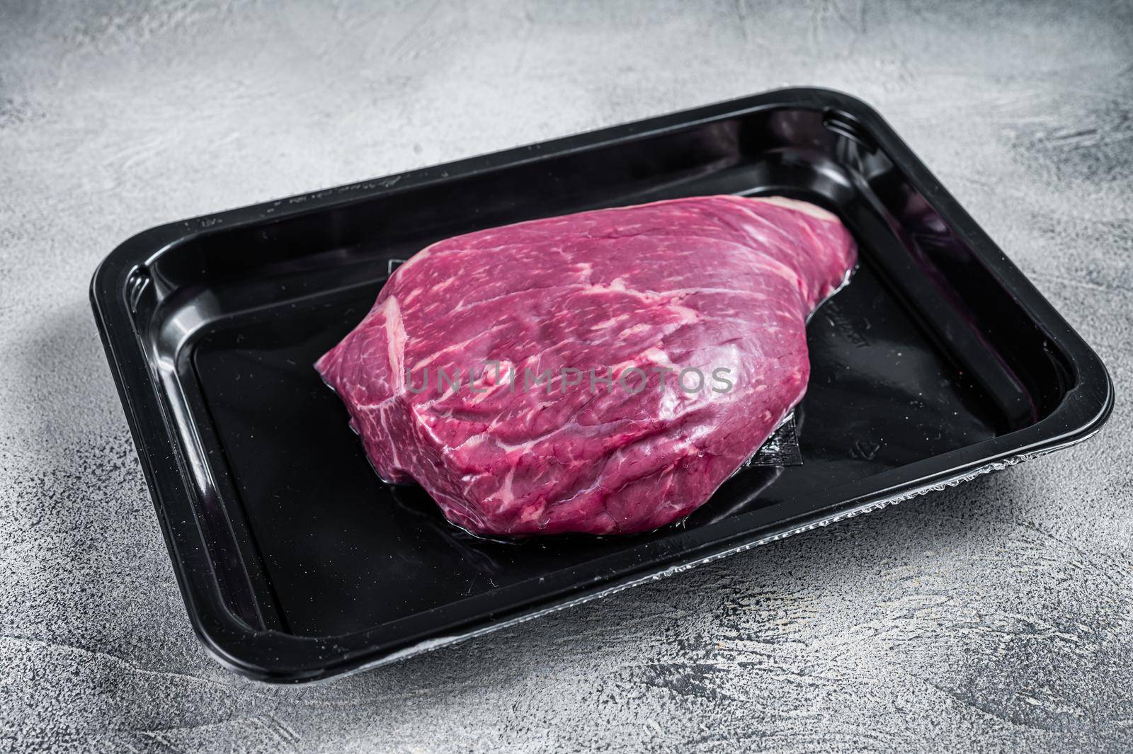 Raw cap rump steak or top sirloin beef meat steak in vacuum packaging. White background. Top view by Composter