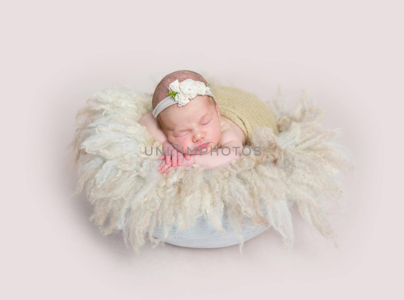 Adorable girl sleeping on huge soft fury pillow, wearing cute little headband