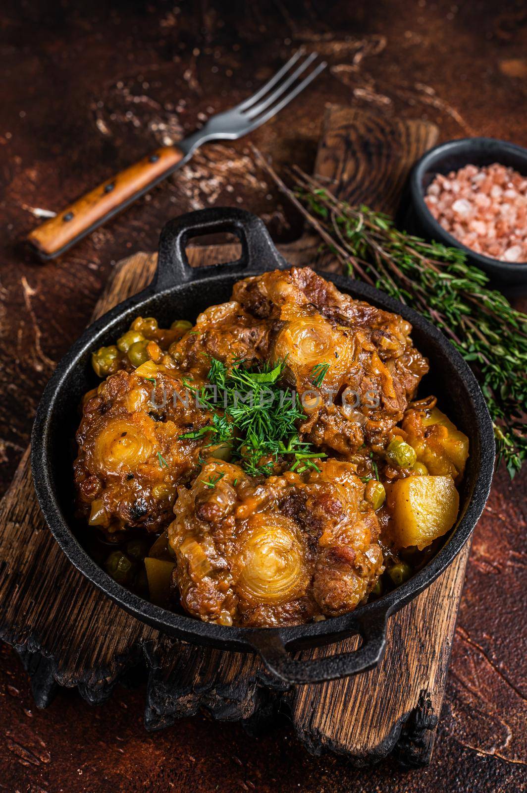 Beef oxtails stew with wine and vegetables in a pan. Dark background. Top view by Composter