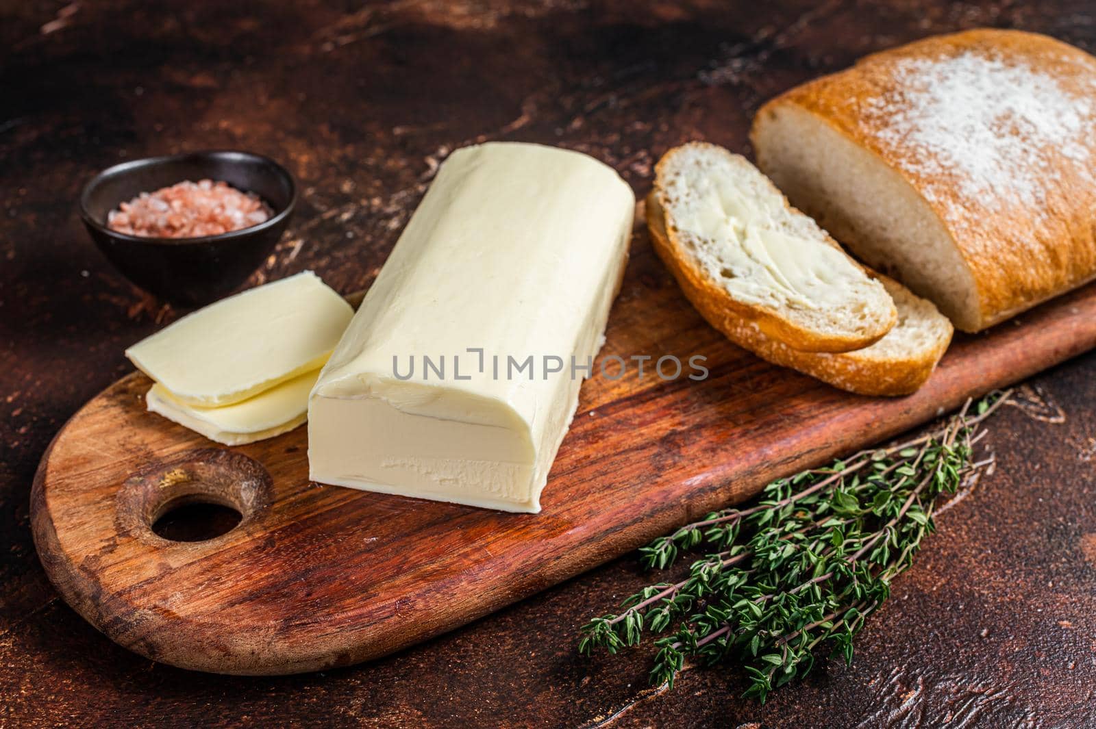 Butter spread and foodstuff toasts on a wooden cutting board. Dark background. Top view by Composter