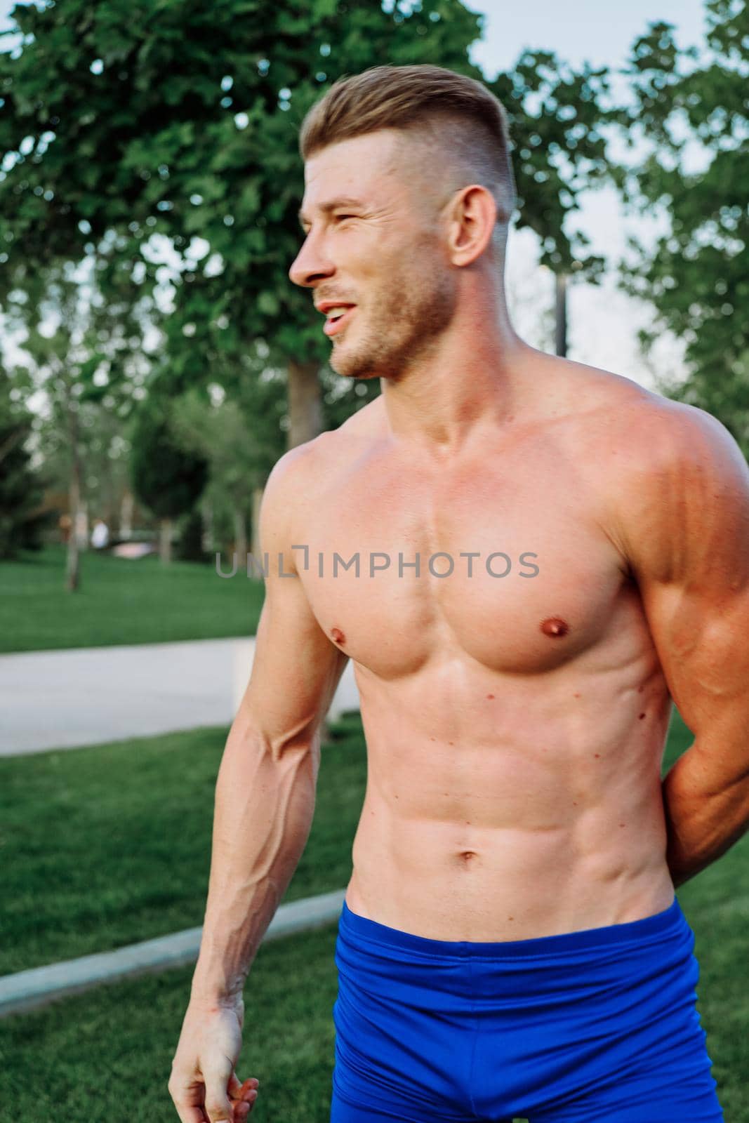 sporty muscled man with naked torso in a workout park by Vichizh