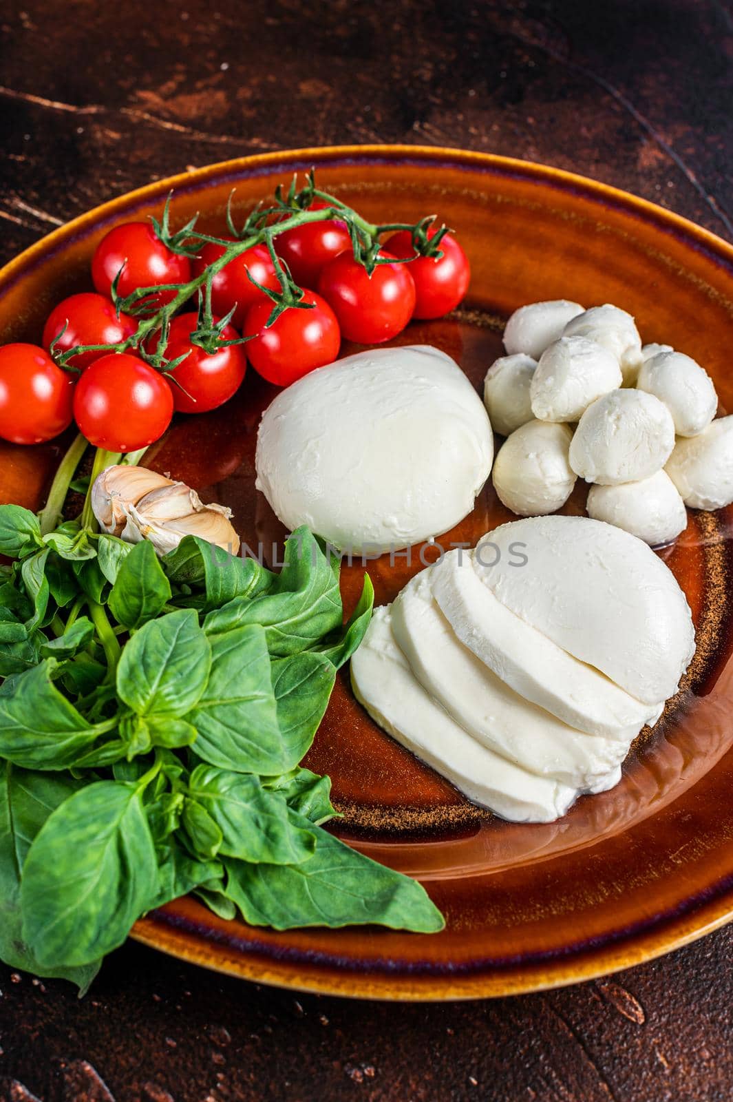 Mozzarella cheese, basil and tomato cherry ready for cooking Caprese salad. Dark background. Top view by Composter