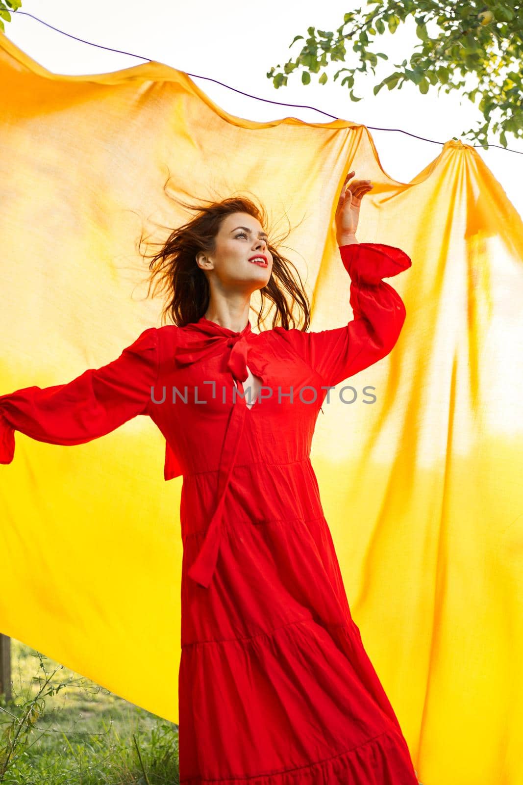 pretty woman in red dress yellow fabric on nature background. High quality photo