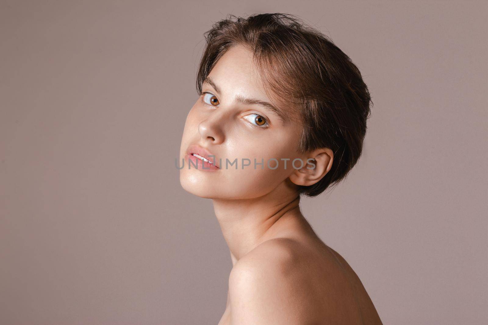 Beautiful young woman with absolutely no makeup on a neutral gray background