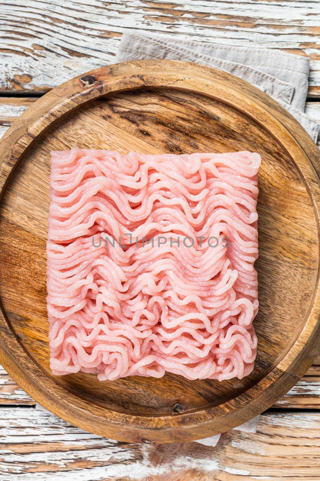 Raw mince or ground chicken meat on wooden board. White background. Top view.