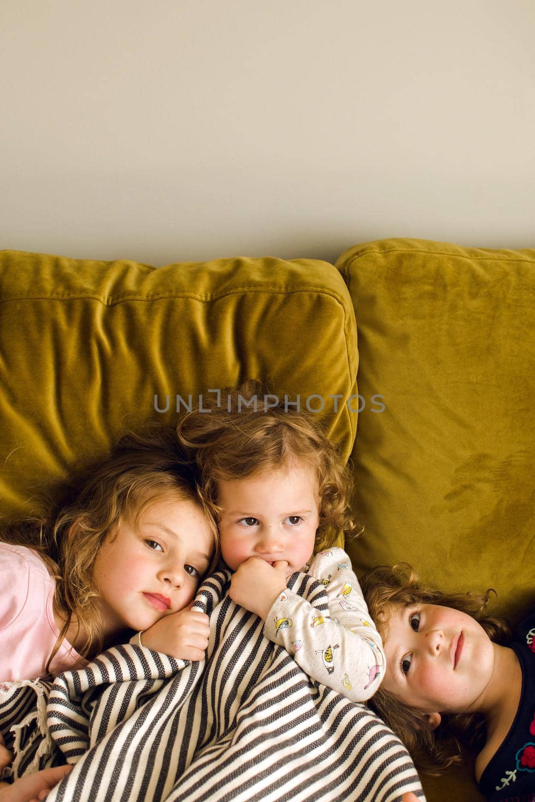 Cute little girls chilling on soft couch in living room together at home