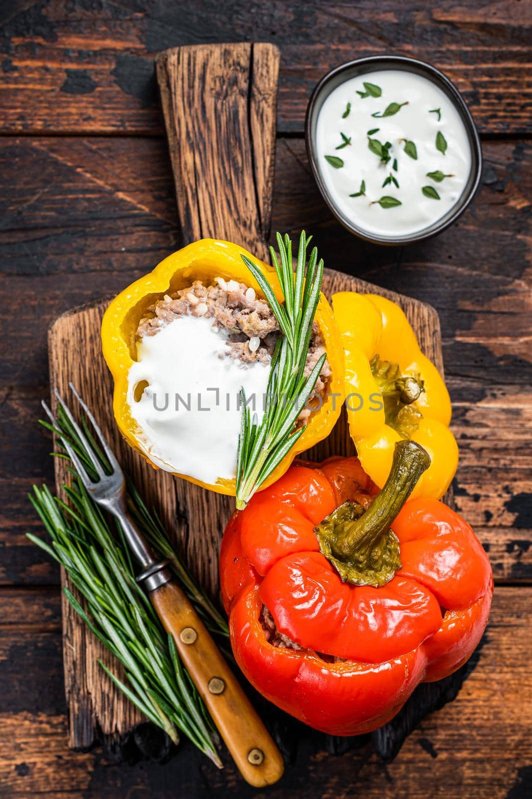 Roast bell pepper stuffed with beef meat, rice and vegetables on a wooden board. Dark wooden background. Top view.