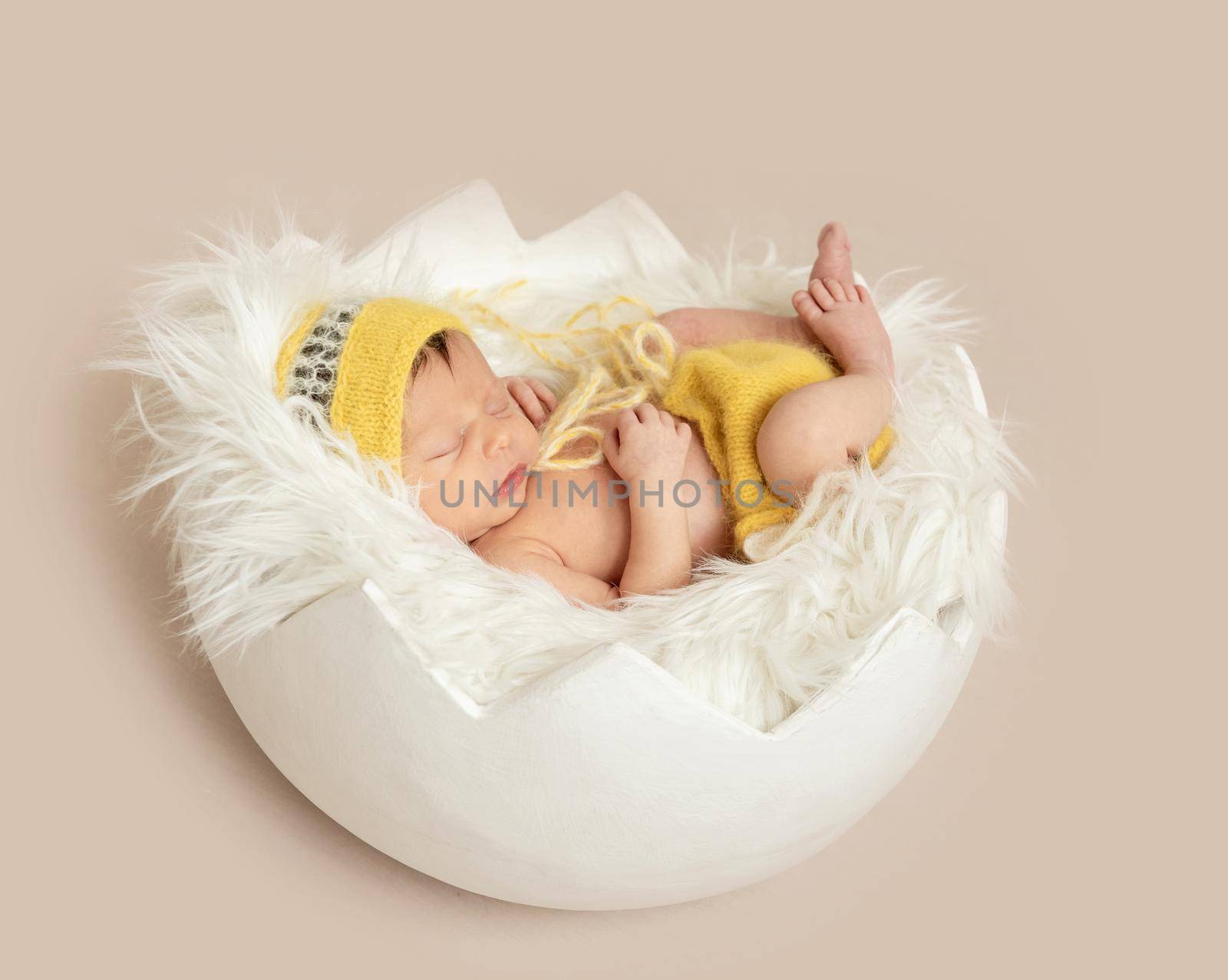 funny sleeping baby in yellow romper with chicken toy on round cot, top, view