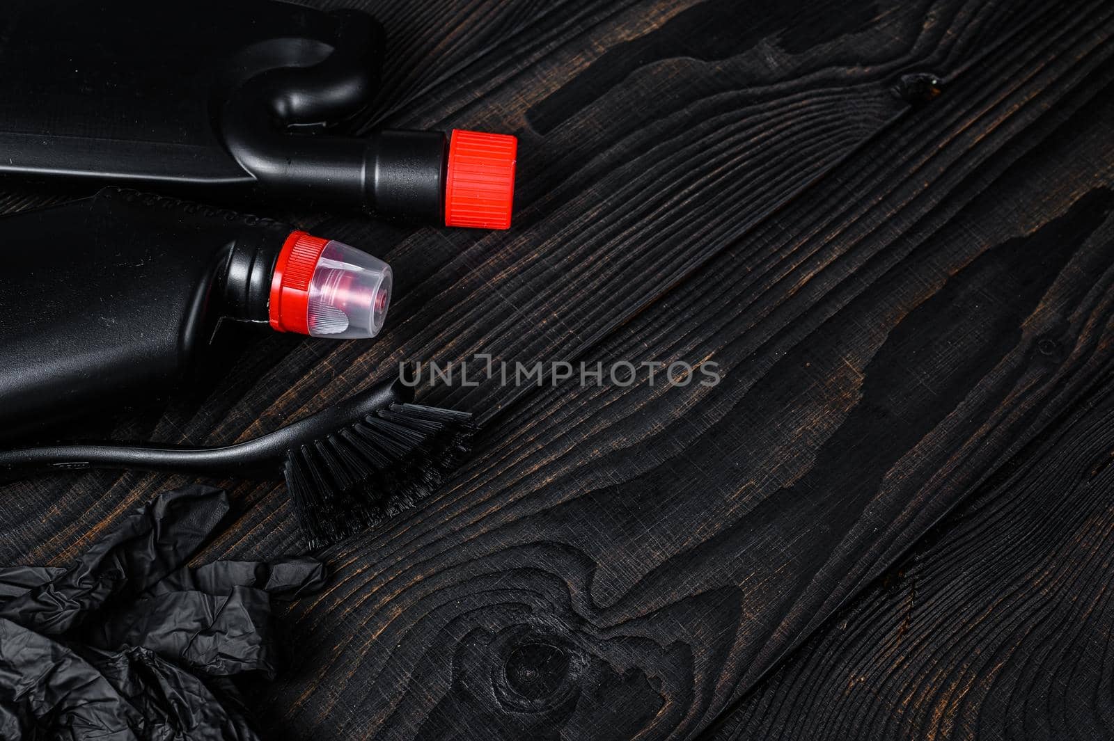 Black style Home cleaning service concept with supplies. Black wooden background. Top view. Copy space.