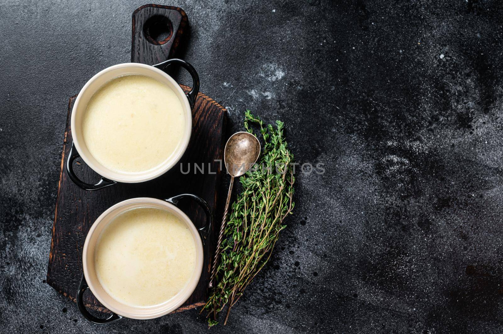 Potato cream soup in bowls on kitchen table. Black background. Top view. Copy space by Composter