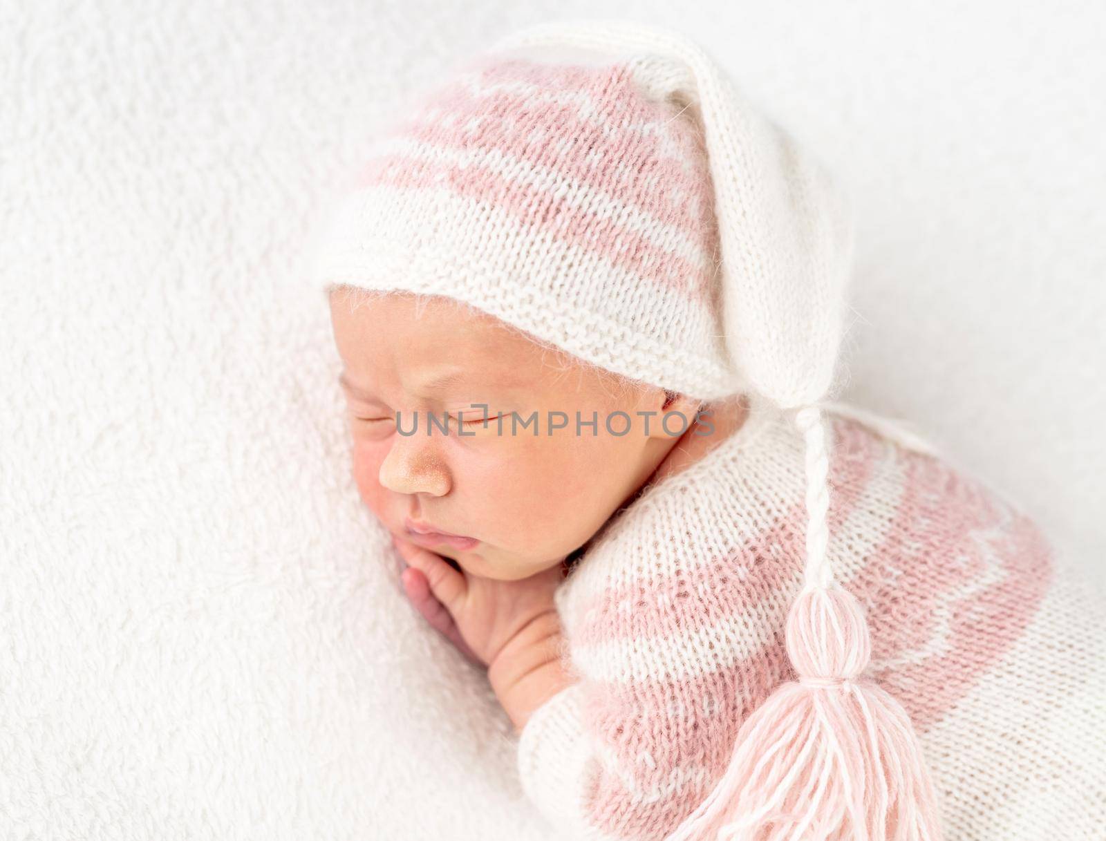 Pretty baby girl in creamy knitted suit and hat, isolated on white background