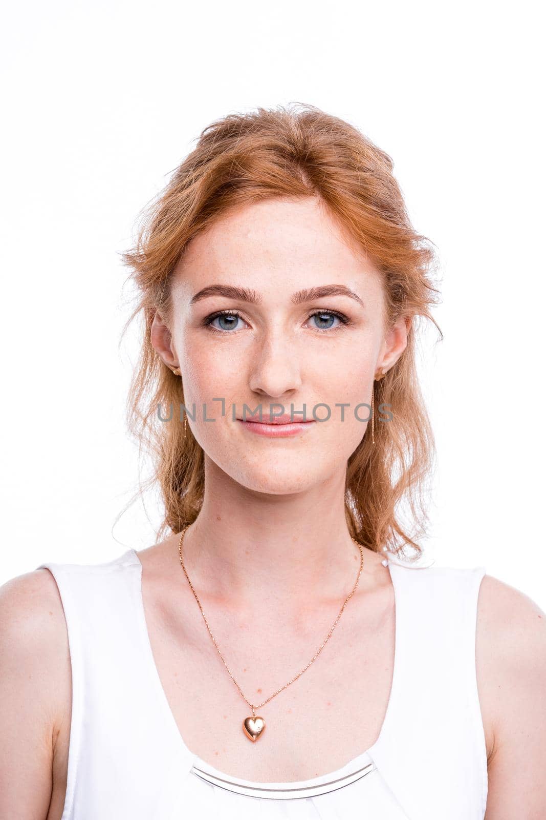 Portrait of a beautiful young woman of European, Caucasian nationality with long red hair and freckles on her face posing on a white background in the studio. Close-up student girl in a white blouse by Tomashevska