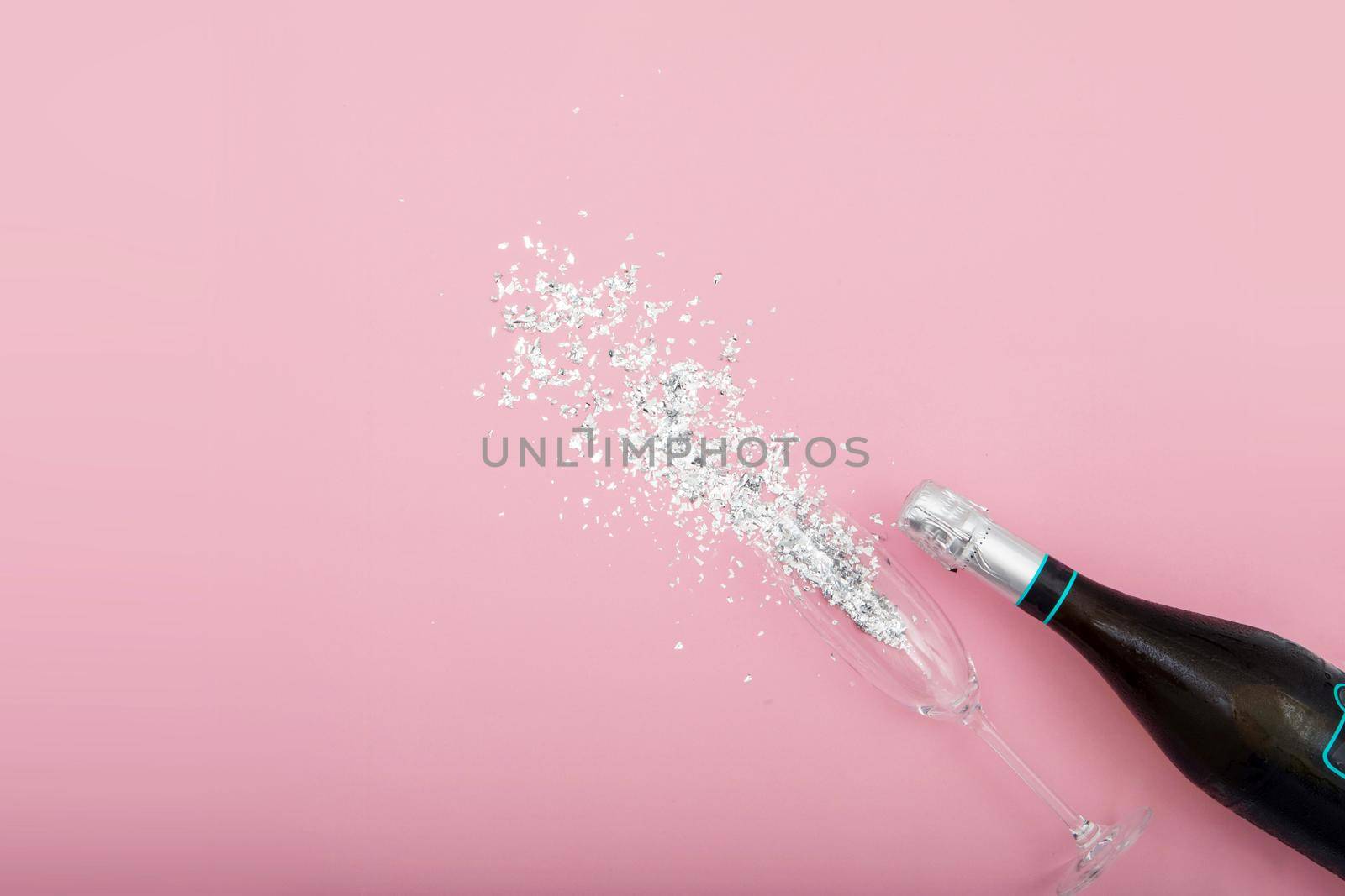 Bottle of champagne and glass on pink table with glitter by Demkat