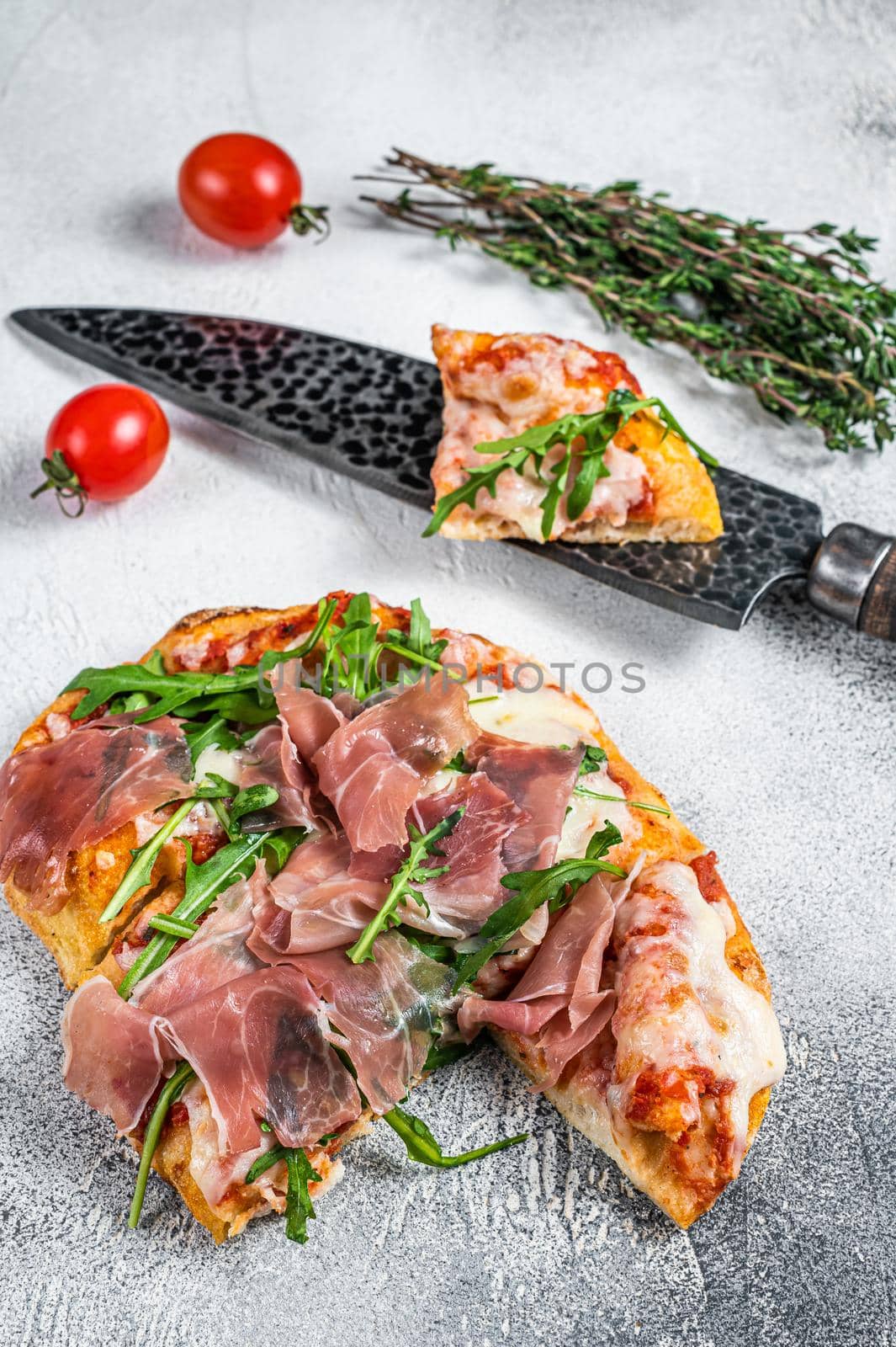 Italian Pizza with parma ham, arugula and cheeseon a kitchen table. White background. Top view by Composter