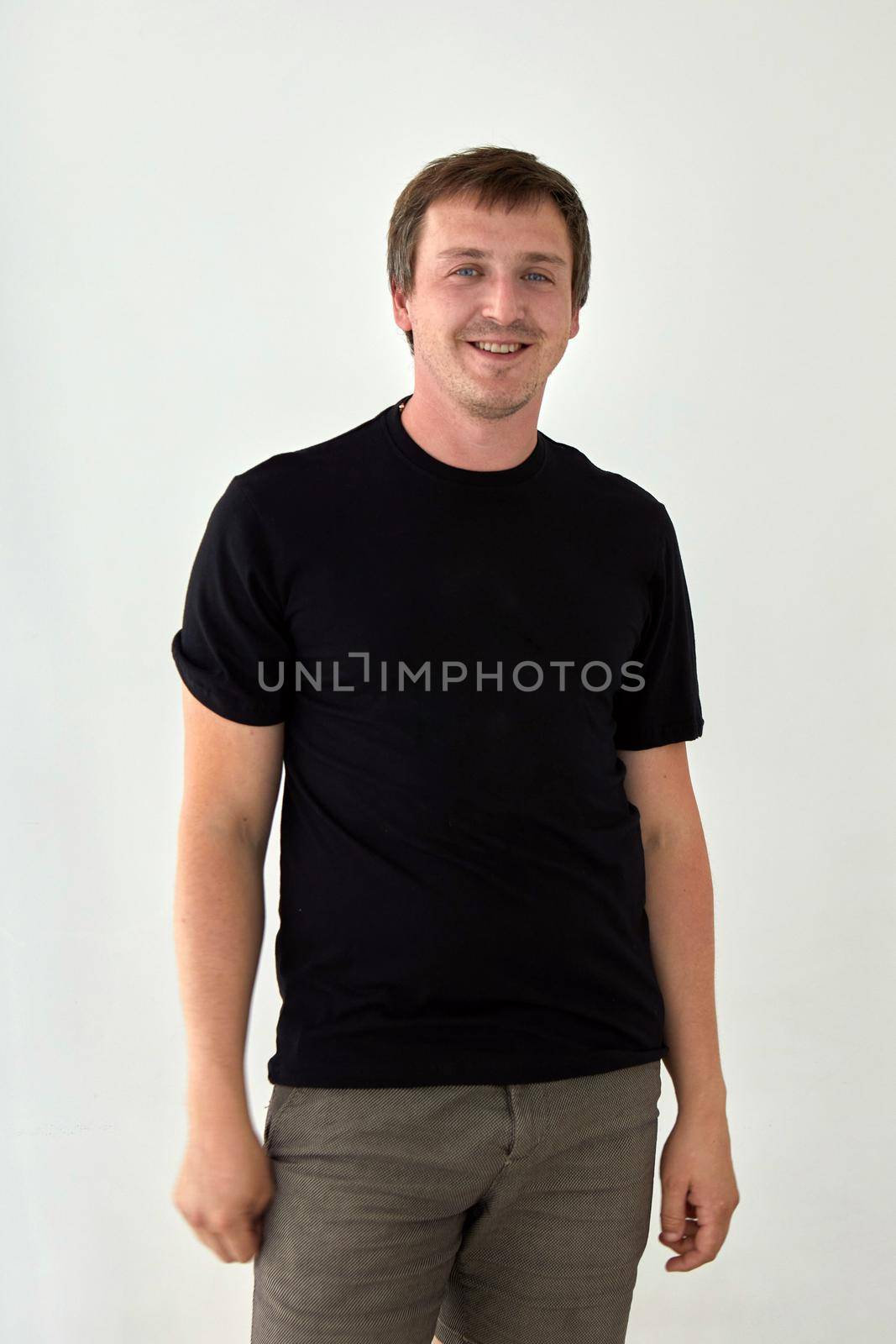 Young male model wearing basic black t shirt with space for print standing against white background