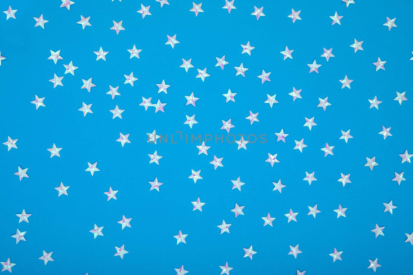 Blue background with shiny iridescent pearl stars. Festive trendy blue background with silver metallic stars