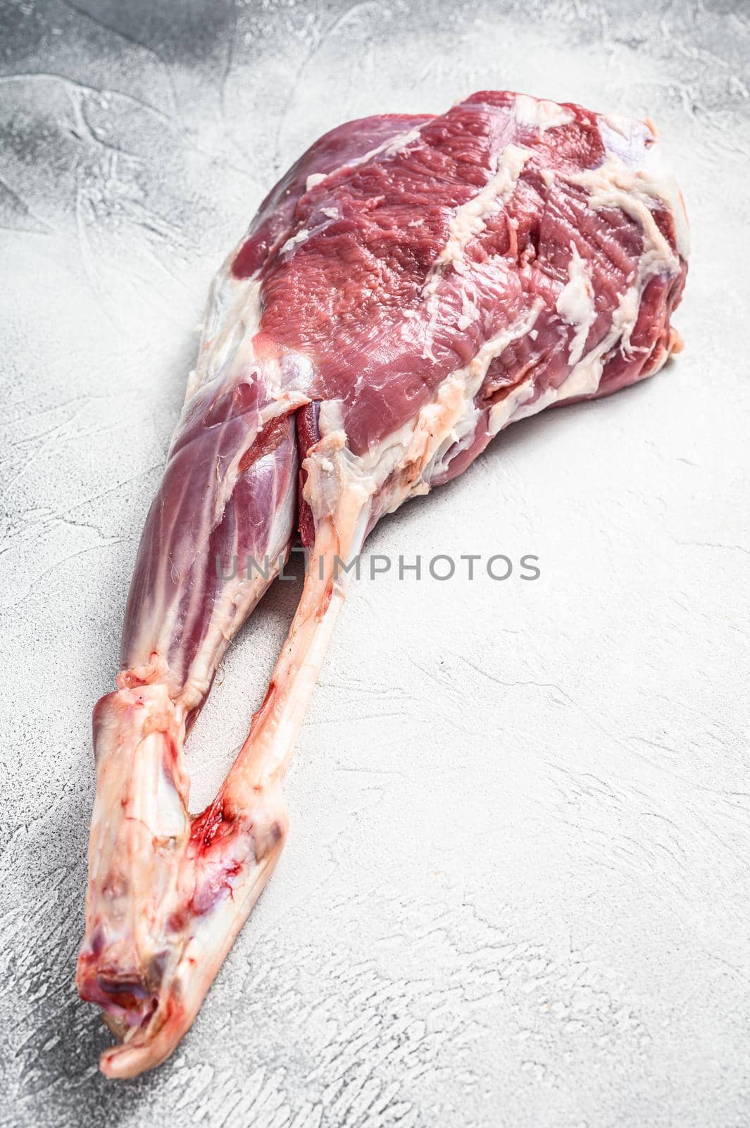 Goat leg with pepper and garlic. Raw Farm meat. White background. Top view.