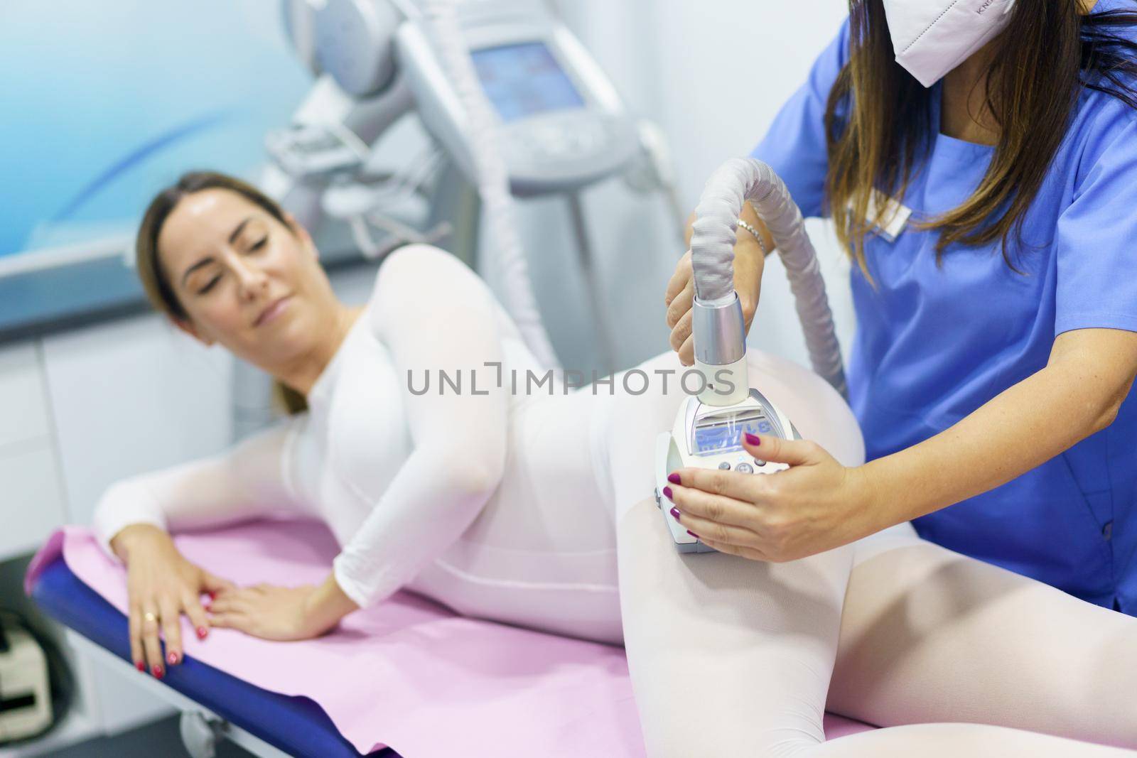 Woman in special white suit having a anti cellulite massage with spa apparatus by javiindy