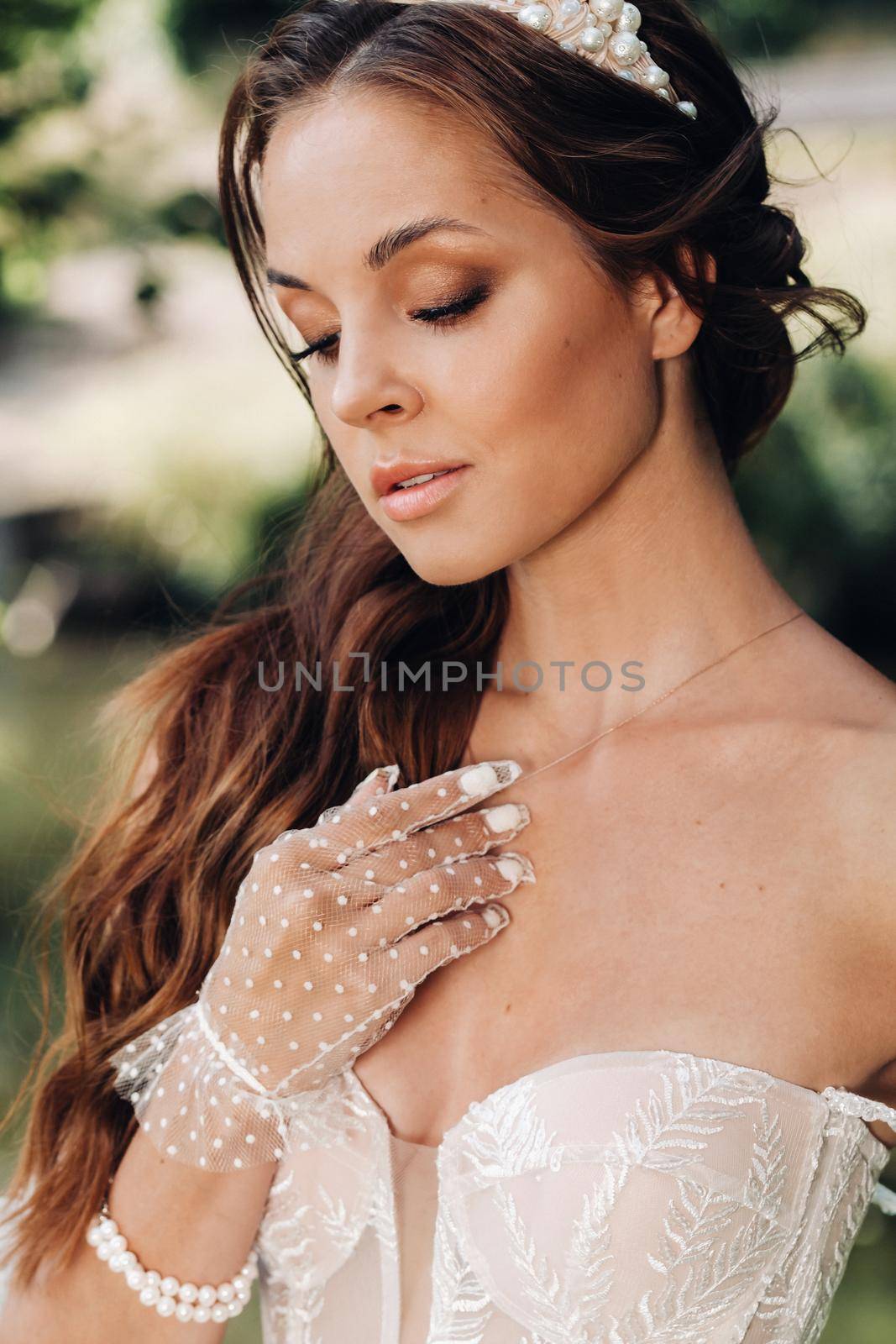 An elegant bride in a white dress, gloves with a bouquet on a waterfall in the Park, enjoying nature.Model in a wedding dress and gloves in the forest.Belarus.