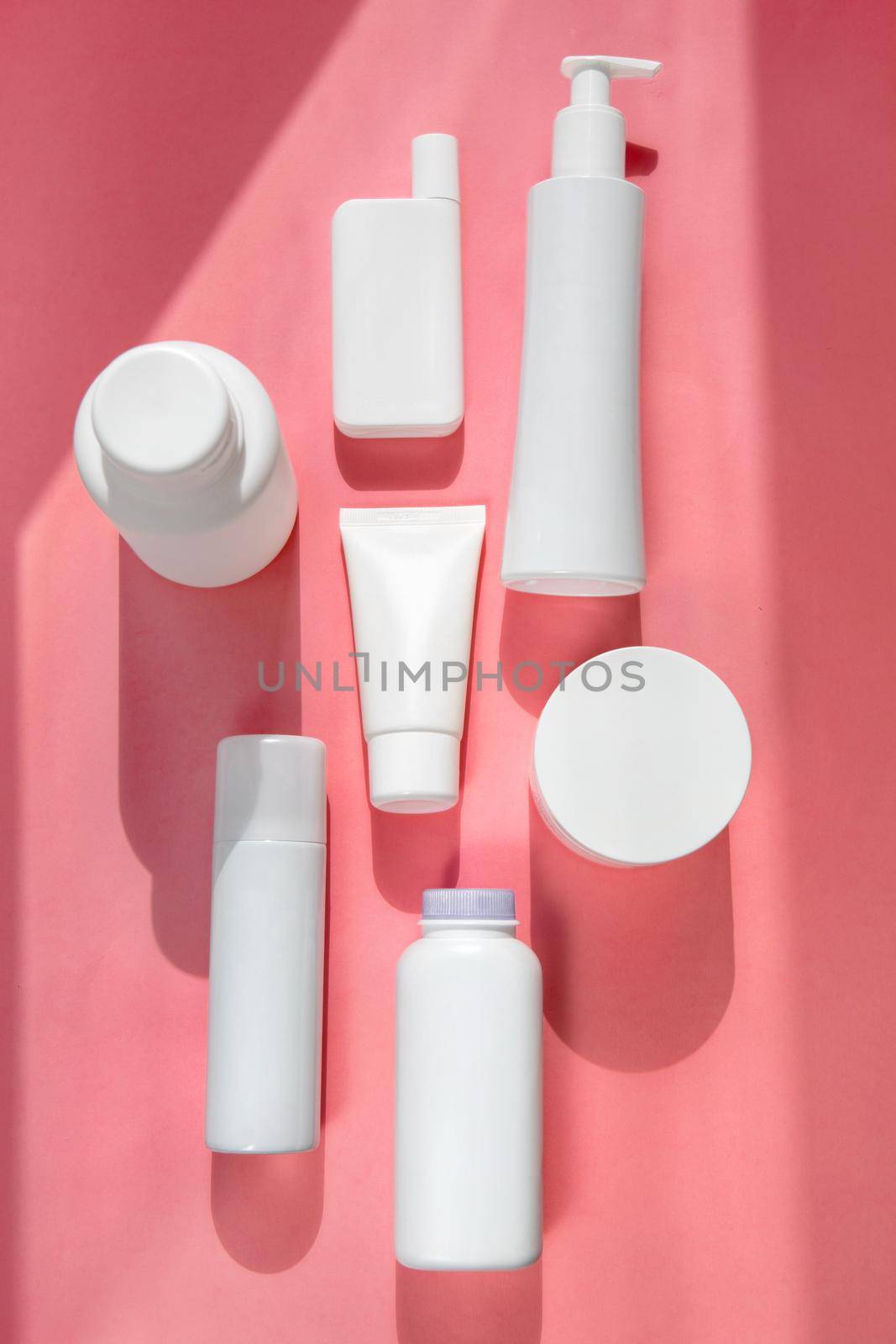 White different types tubes for cosmetics on pink background flatley