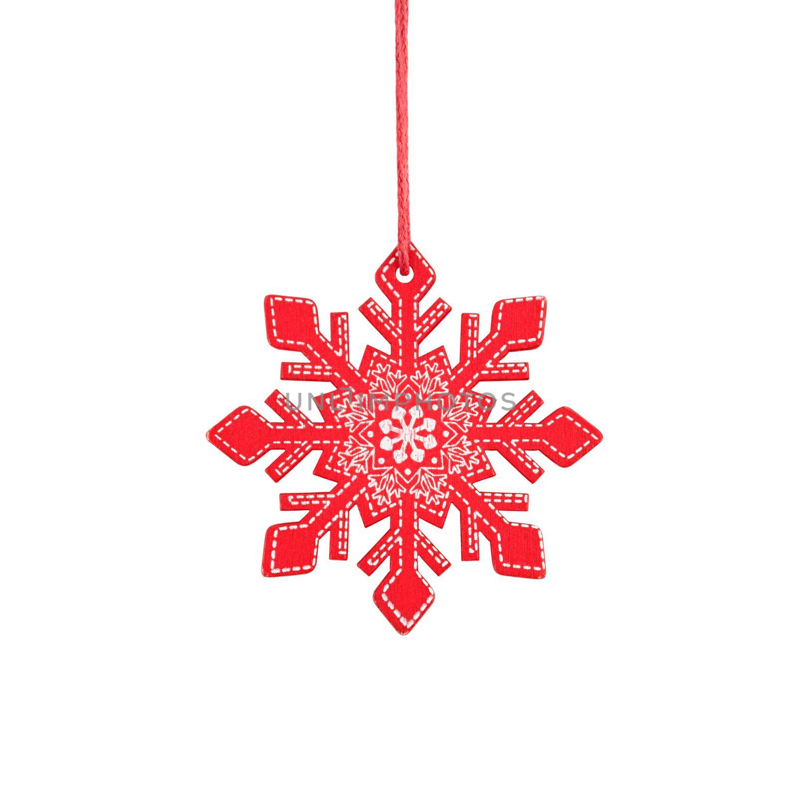 Hanging red wooden snowflake, rustic Christmas tree ornament isolated on a white background.