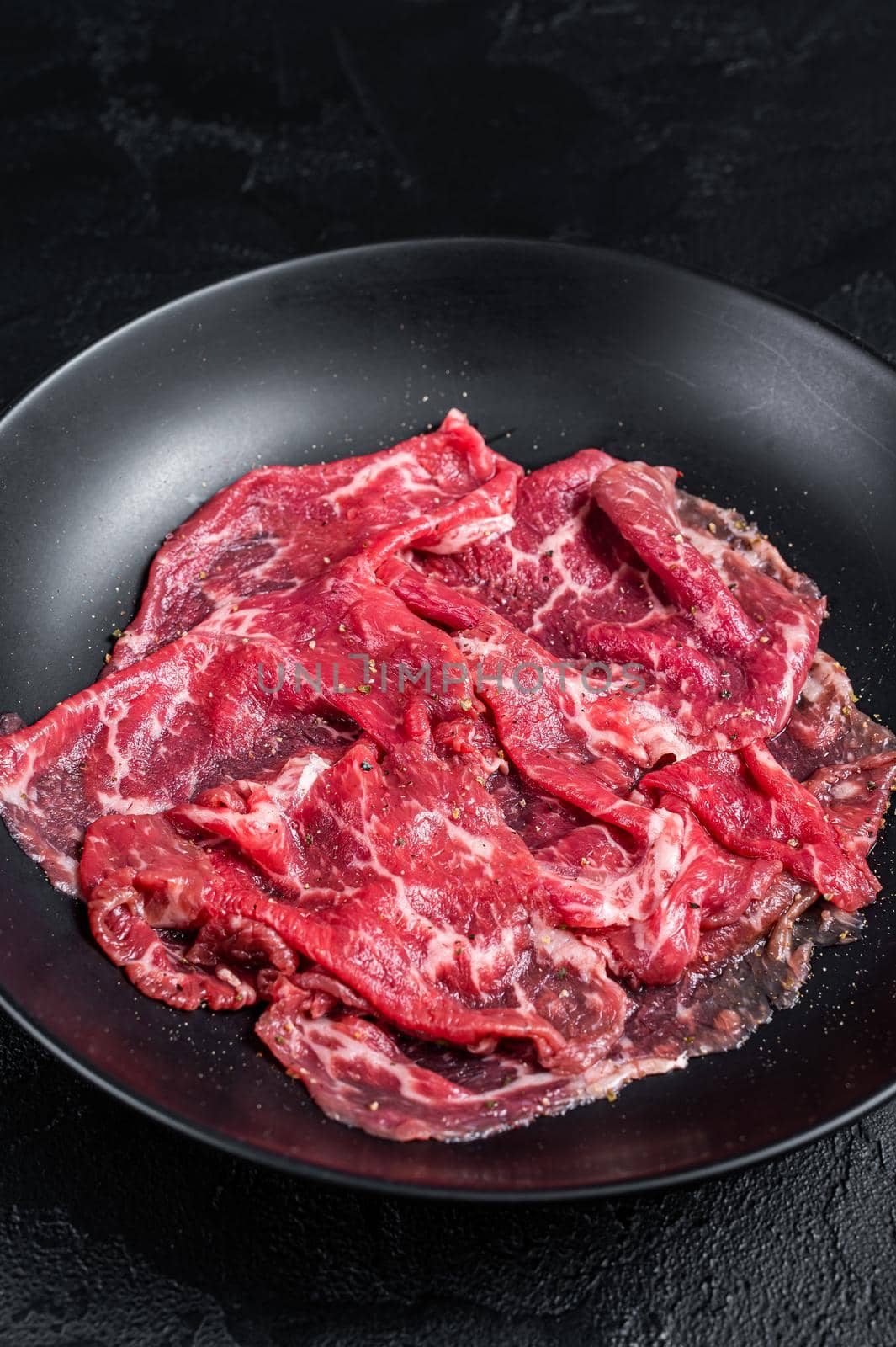 Marbled beef meat carpaccio. Black background. Top view.