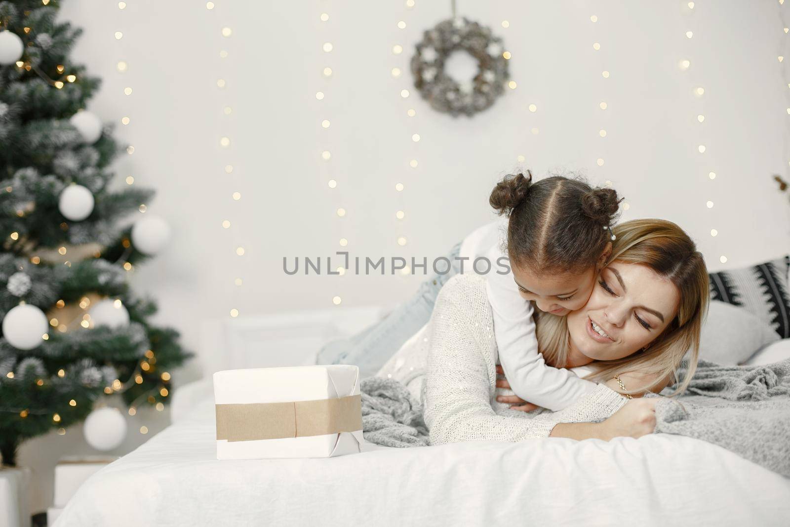 People reparing for Christmas. Mother playing with her daughter. Family is resting in a festive room. Child in a sweater sweater.